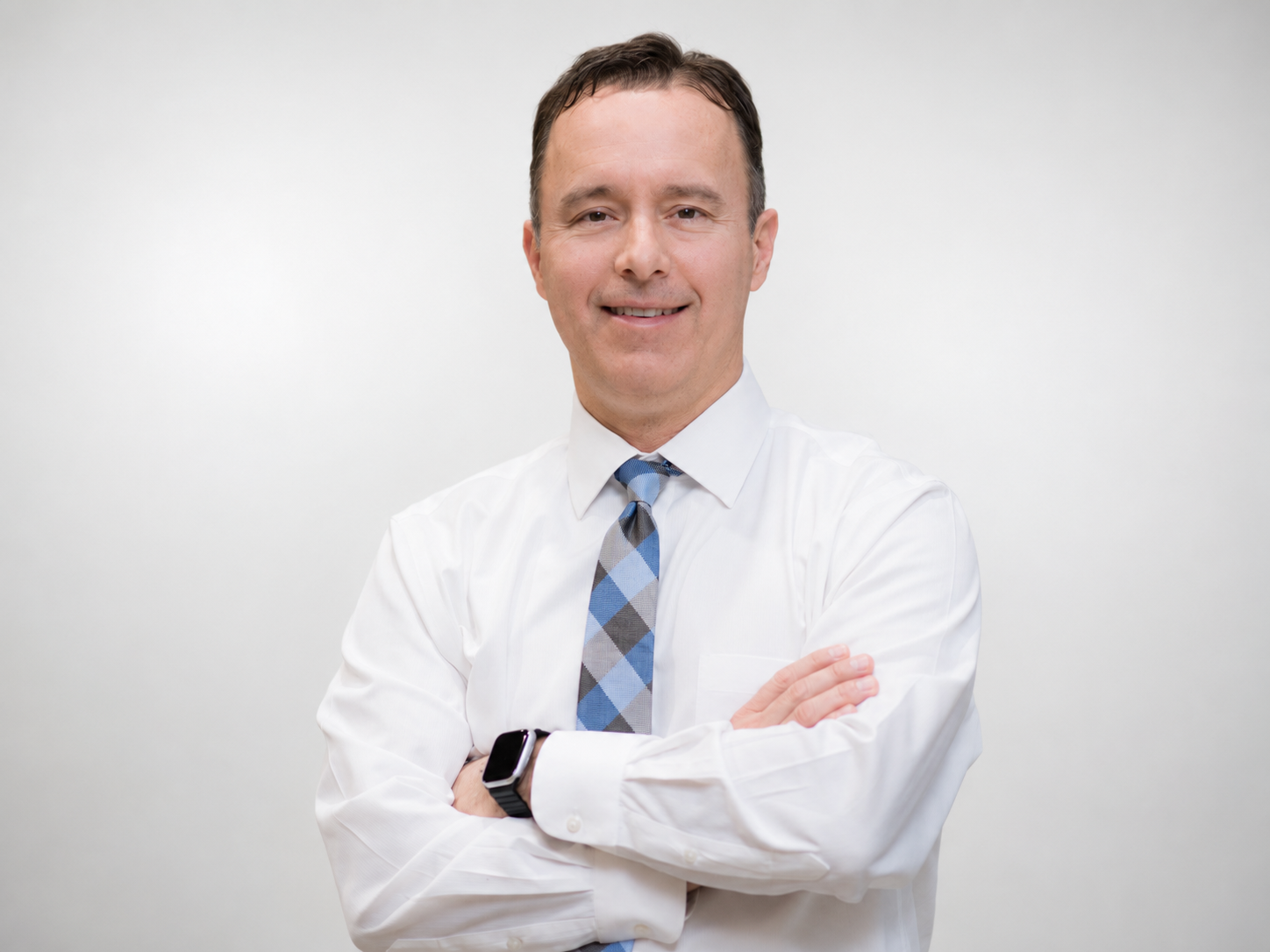 Dr Chad Gonzales, standing with arms crossed, smiling, against a plain white background.
