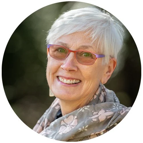 Smiling elderly woman with short white hair and glasses, outdoors