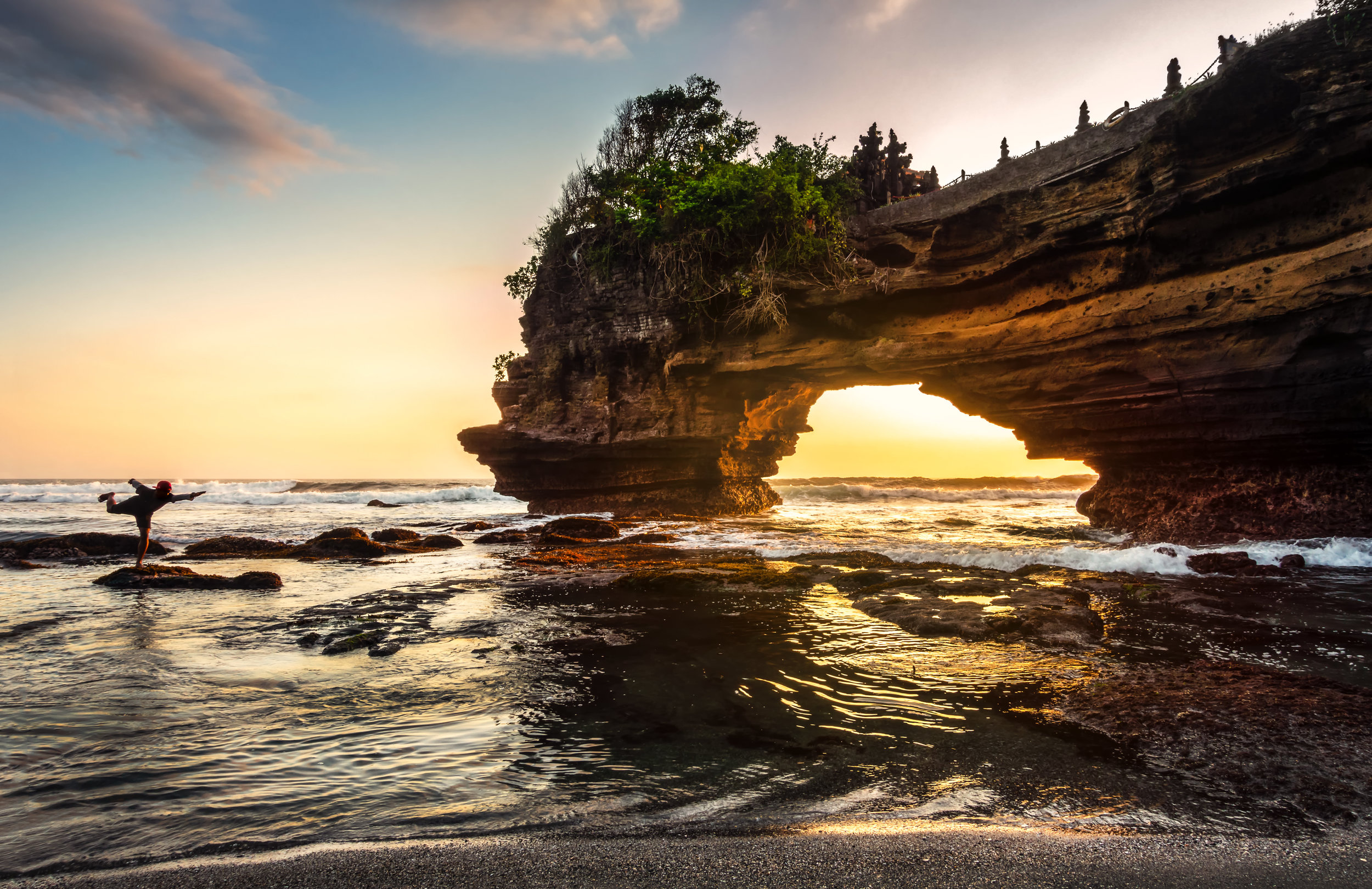 Silhouettes of the man show in sunset background at Pura Batu Bolong Temple, Lombok, Indonesia