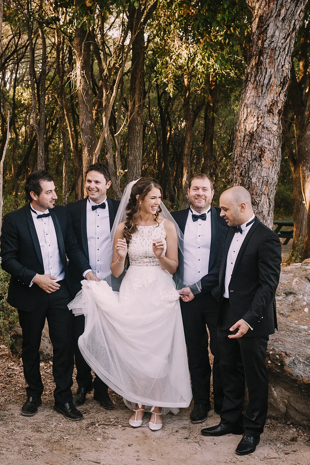 bride laughs with groomsmen at wedding