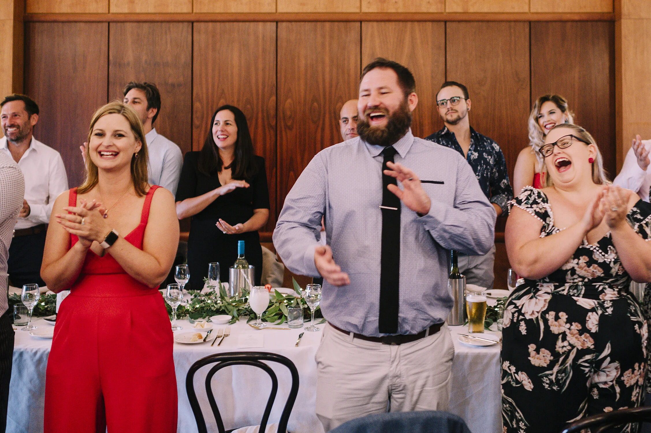 documentary photo of wedding guests at reception clapping and cheering