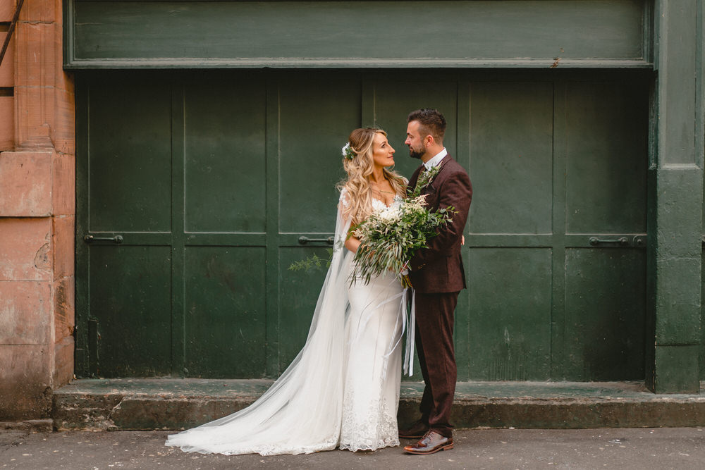  bride and groom look lovingly into each others eyes standing in front of green door wedding photographer scotland prices 