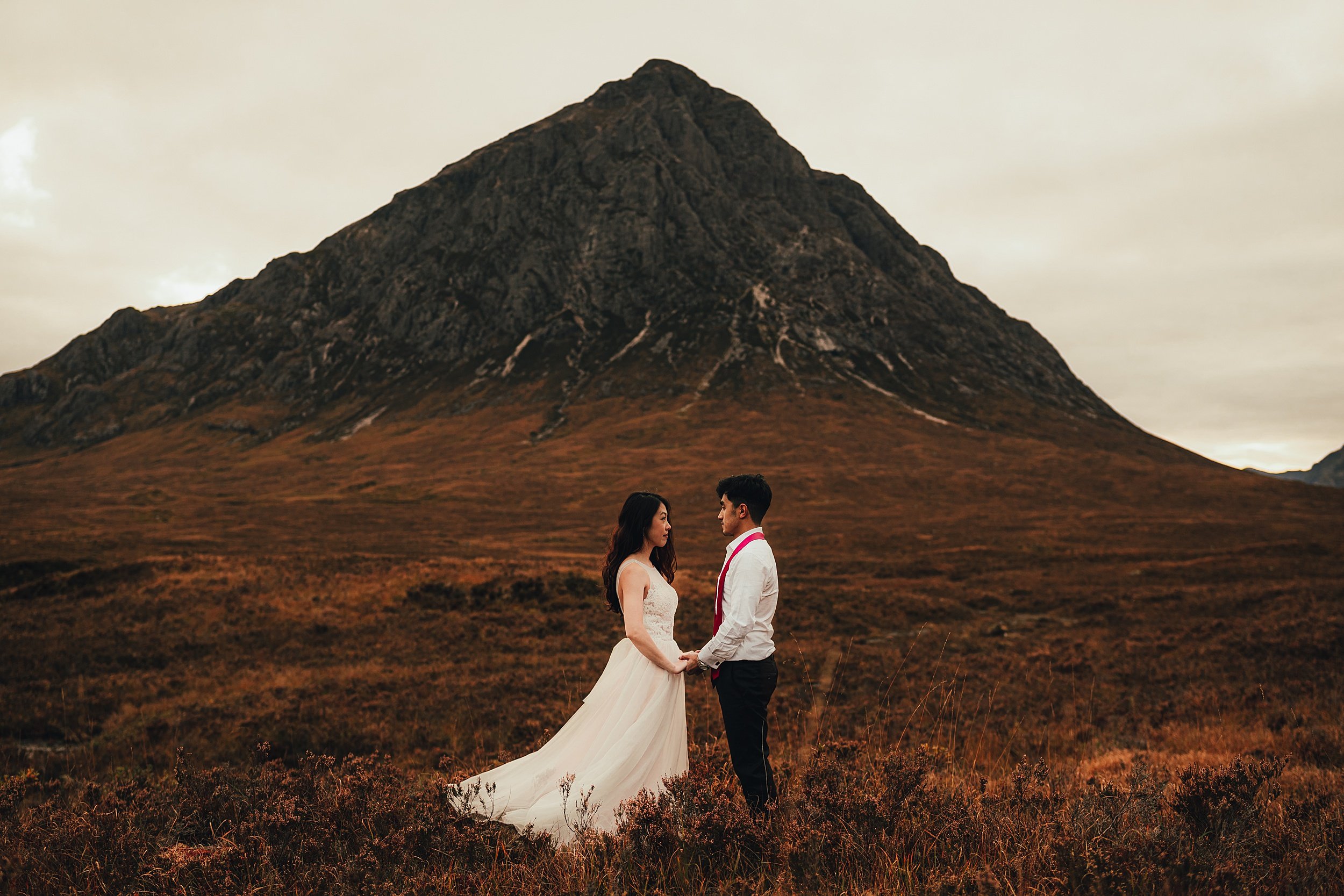 Wedding couple stand at the foot of Buachaille Etive Mòr in Glencoe