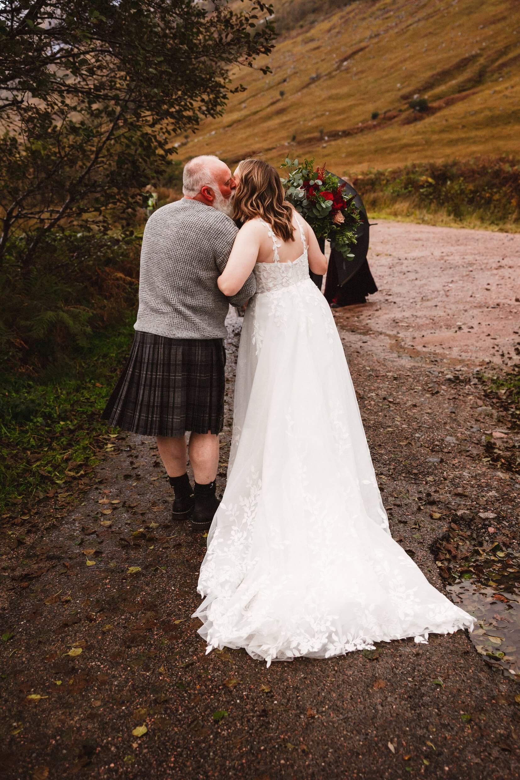 father of the bride gives daughter a kiss before glencoe elopement wedding ceremony in scotland