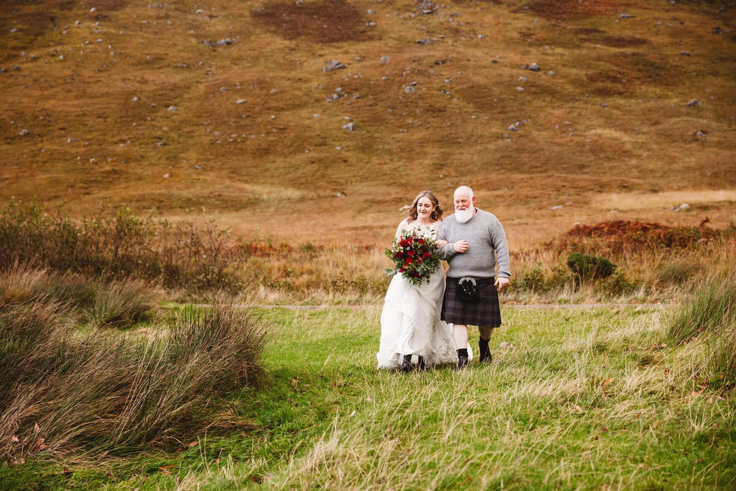 father of the bride and bride walk down aisle during glencoe elopement in scotland