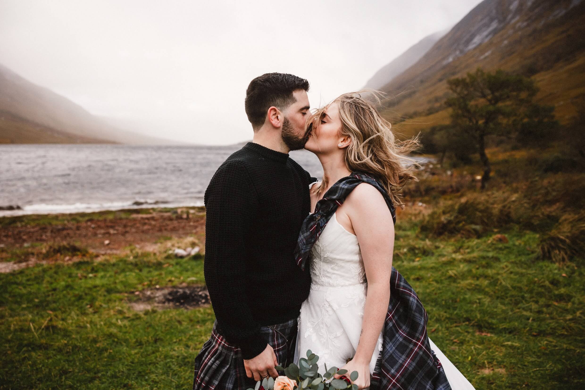 bride and groom kiss in stormy weather during loch etive micro wedding elopement in glencoe scotland
