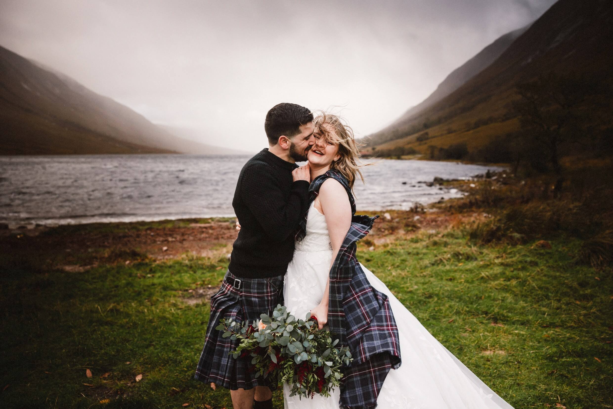 bride and groom in stormy weather during glencoe elopement by loch etive in scotland