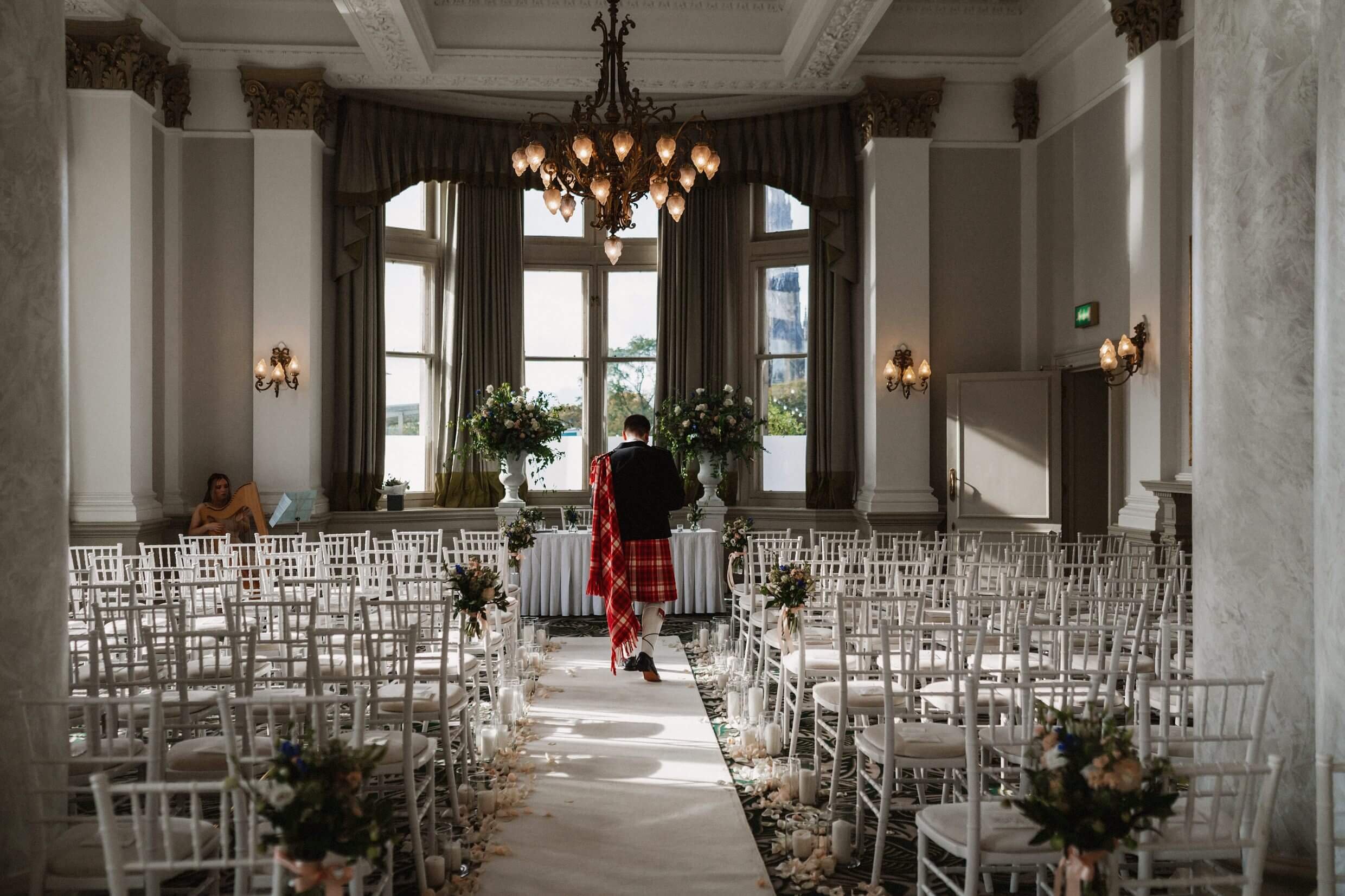 inside interior view of the balmoral hotel edinburgh wedding venue in scotland showing the groom standing at the top of the aisle in front of empty seating