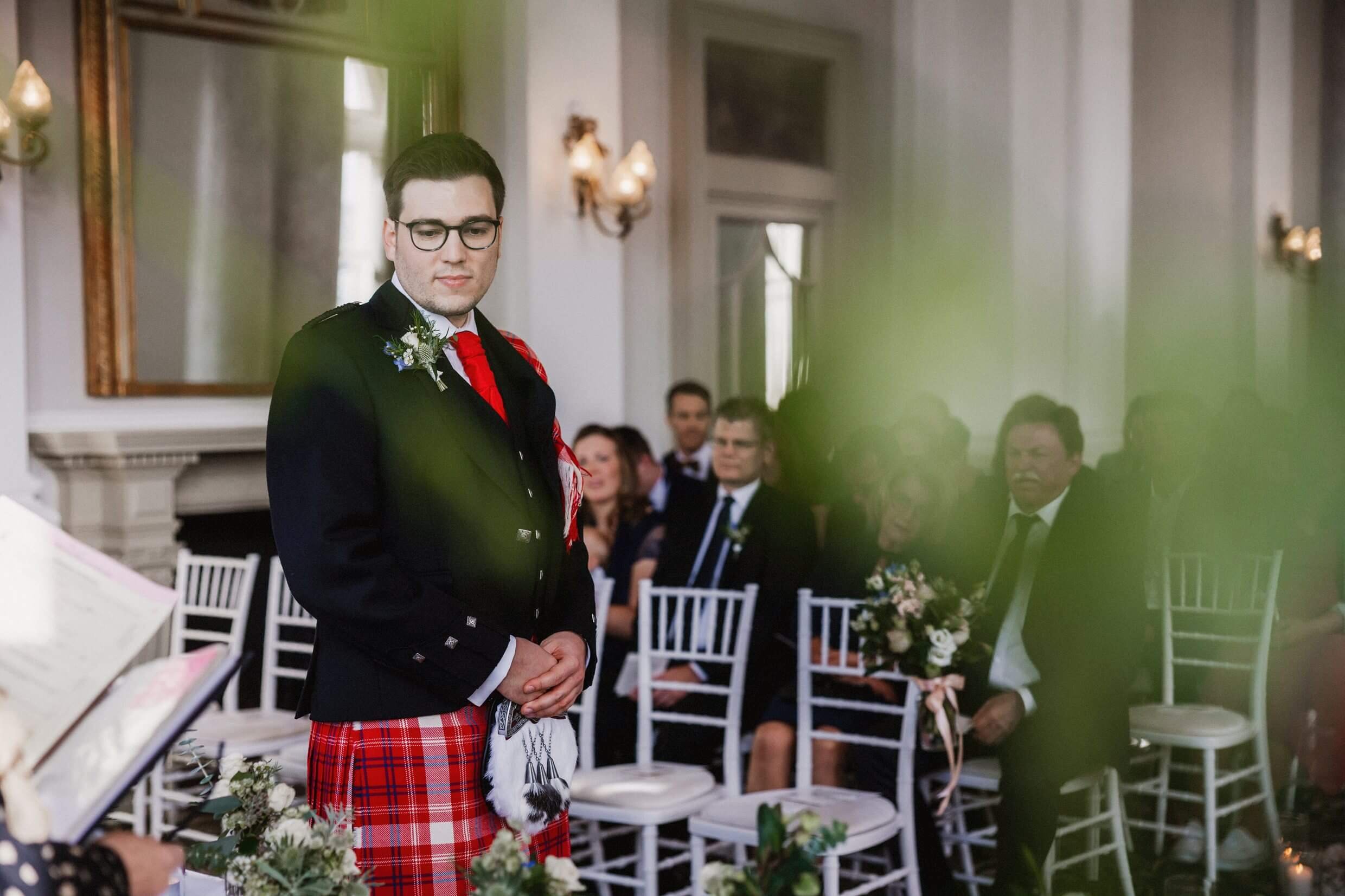 inside interior view of the balmoral hotel edinburgh wedding venue in scotland showing the groom standing at the top of the aisle in front of seated guests