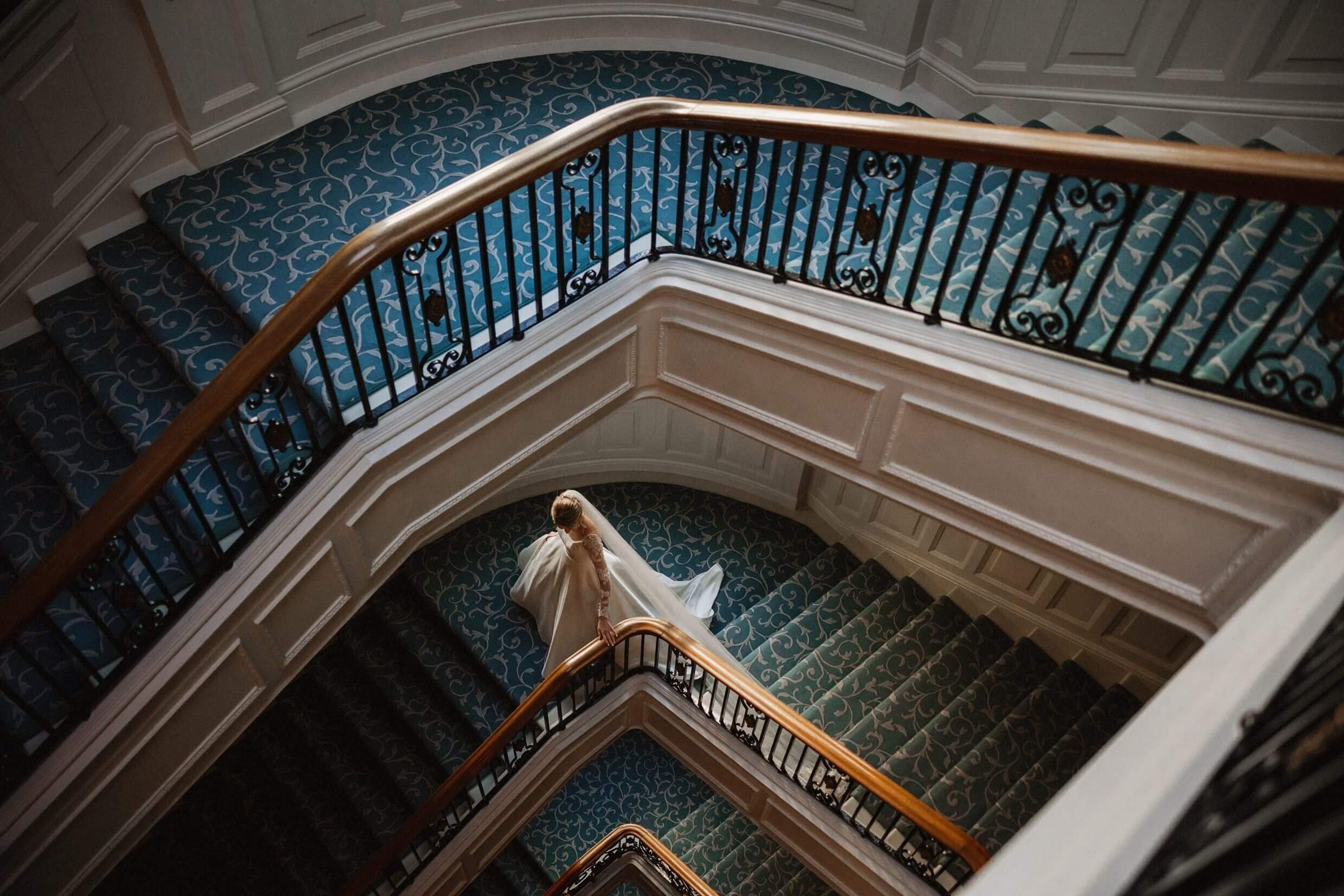 the bride seen from above walking down a staircase at the balmoral hotel edinburgh wedding venue in scotland