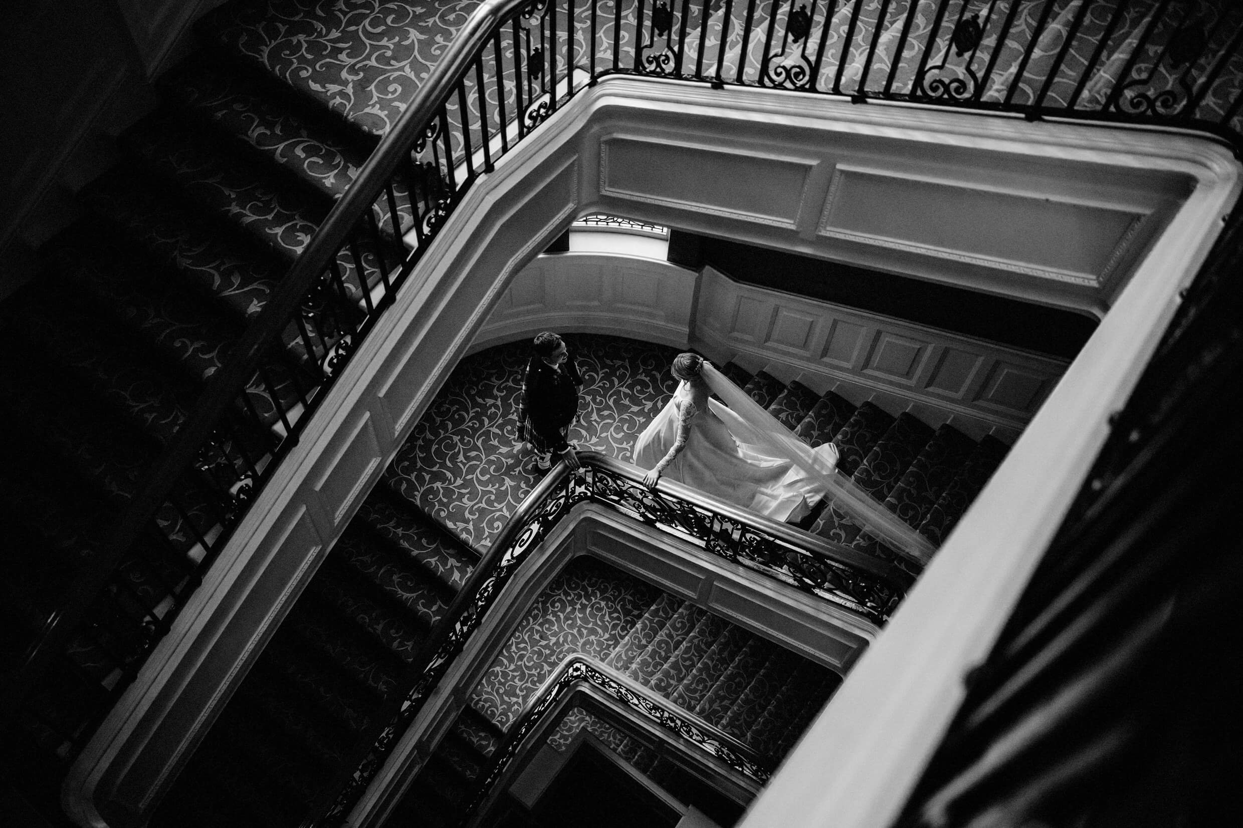 the bride and groom seen from above on a staircase at the balmoral hotel edinburgh wedding venue in scotland
