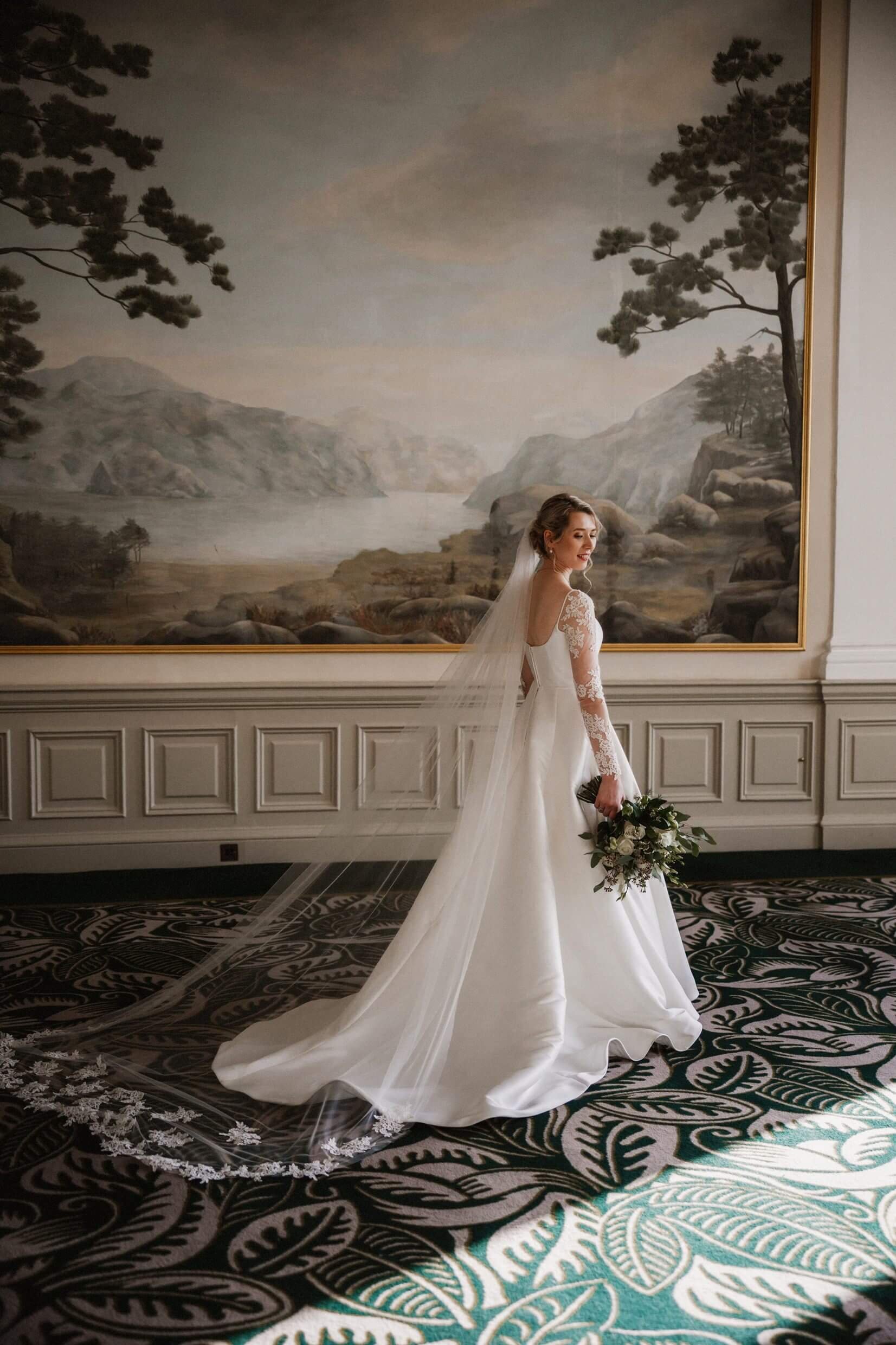 interior inside view of the balmoral hotel edinburgh wedding venue showing the bride standing in front of a large landscape painting