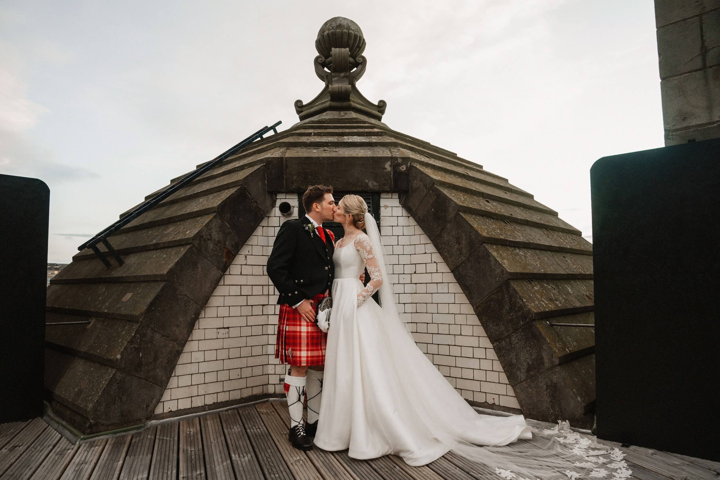 the bride and groom pose for photos on the rooftop of the balmoral hotel edinburgh wedding venue in scotland