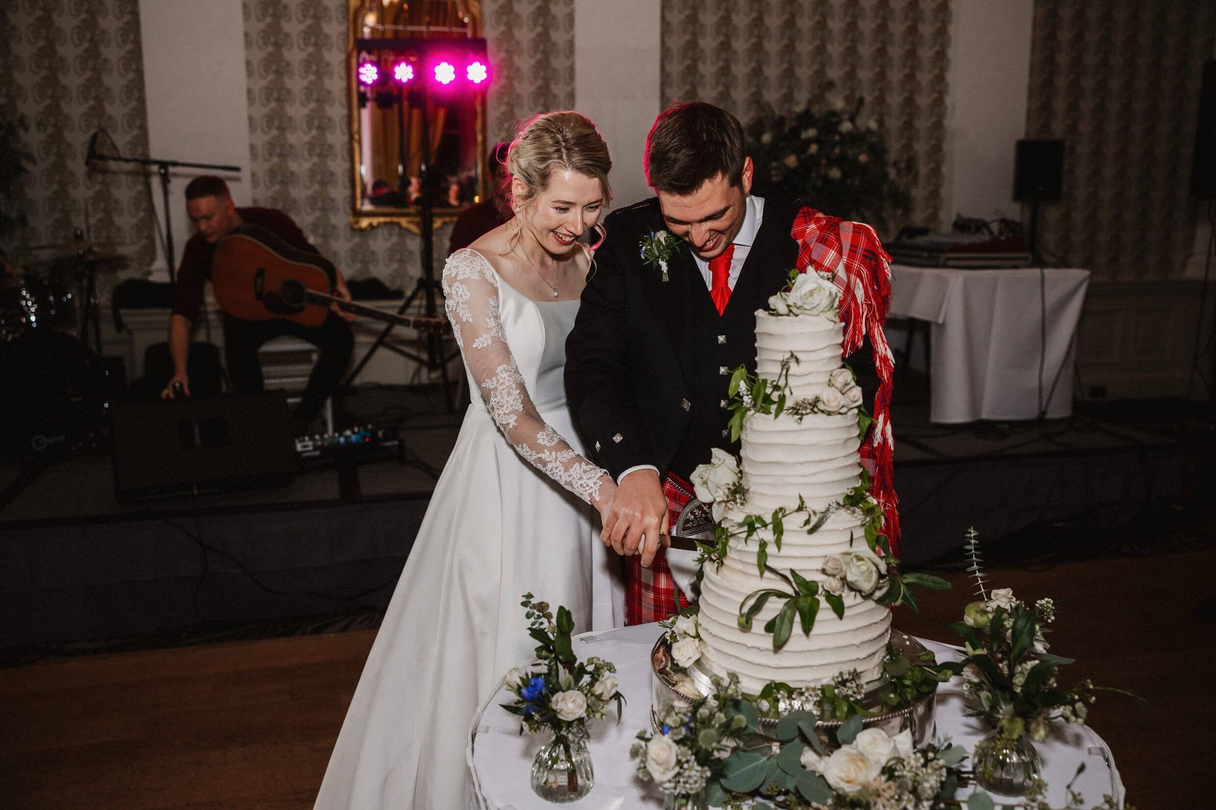 the bride and groom cut their wedding cake at the balmoral hotel edinburgh wedding venue in scotland