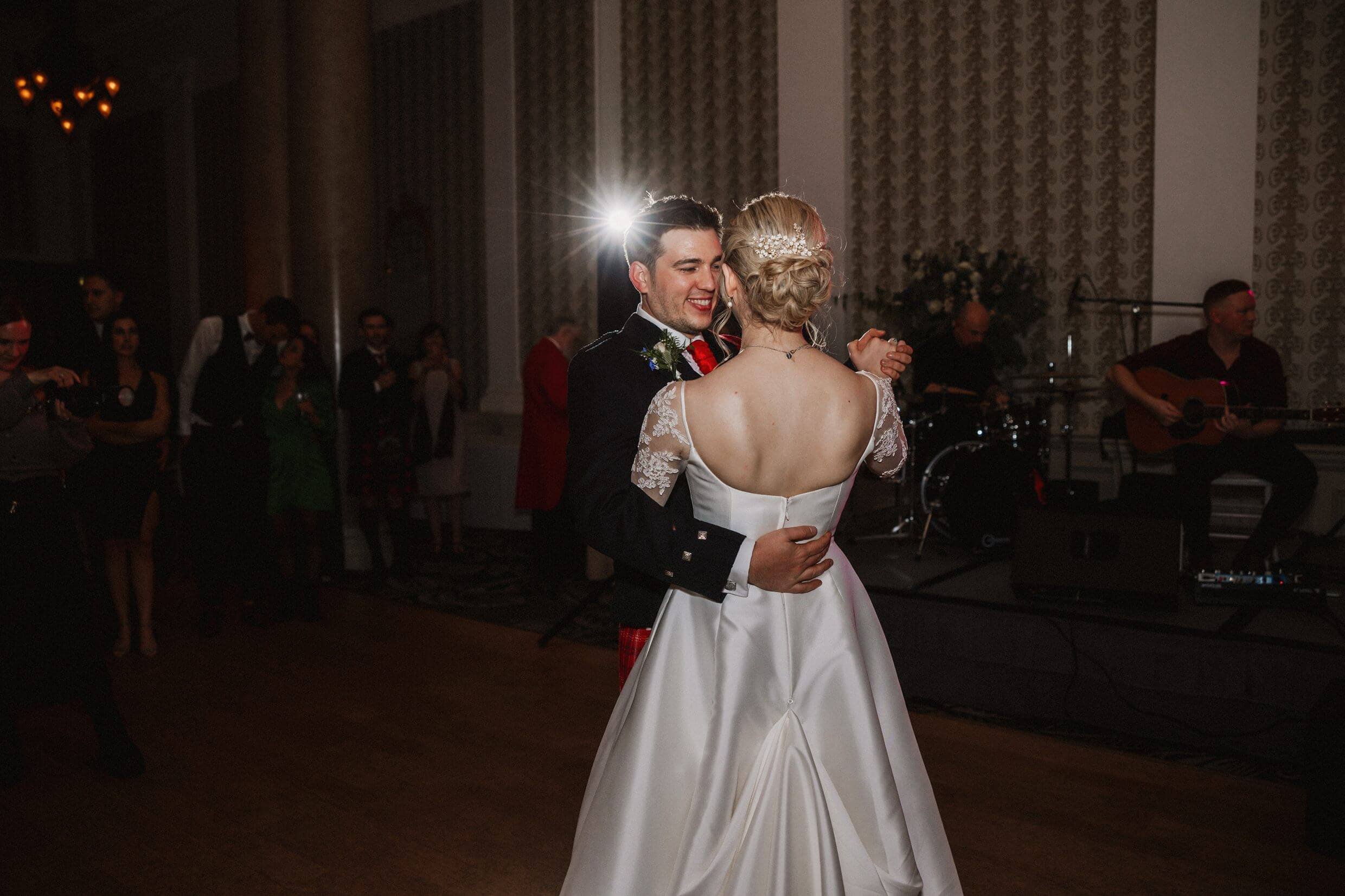 the bride and groom's first dance at the balmoral hotel edinburgh wedding venue in scotland with the band visible in the background