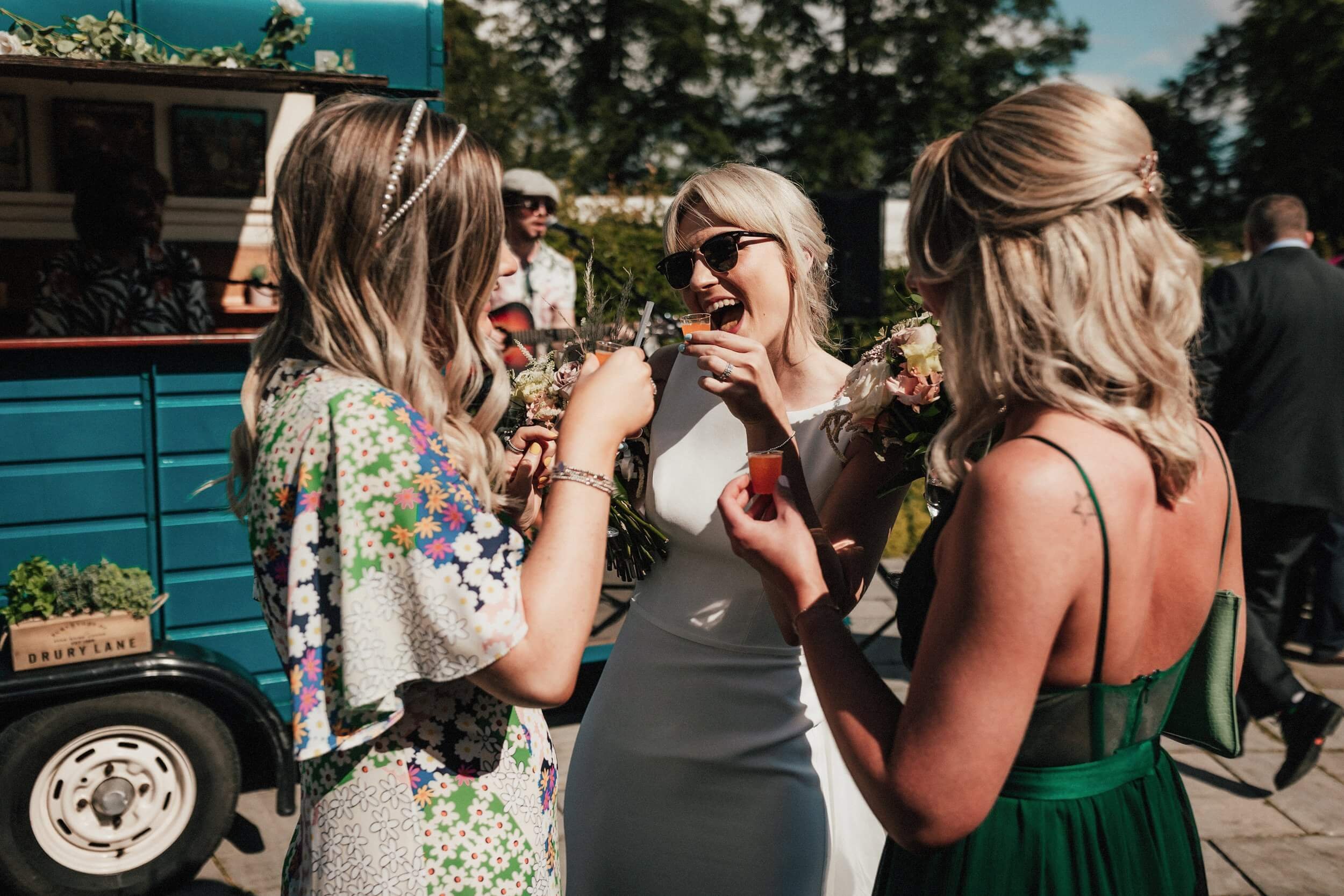 glasgow wedding photographer shoots three female wedding guests chatting outside in front of a blue catering truck