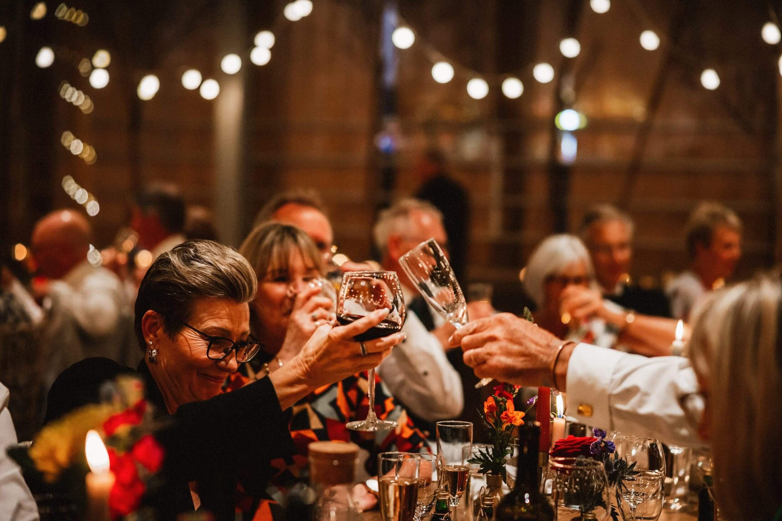 glasgow wedding photographer captures guests at dinner toasting the bride and groom