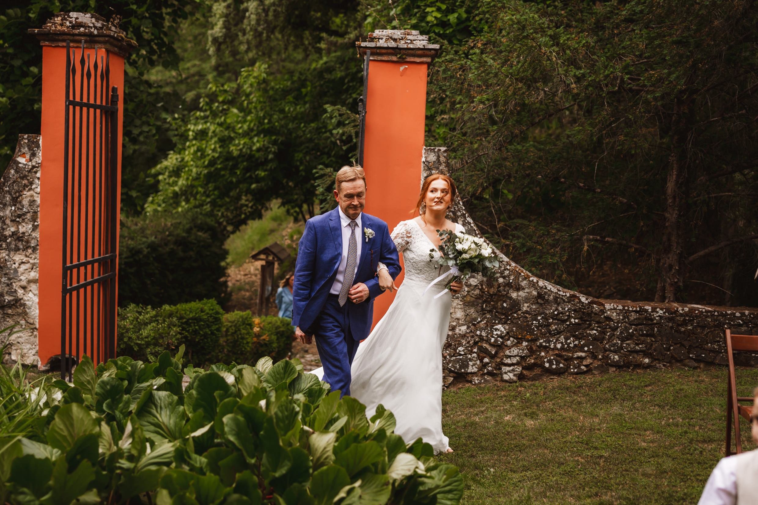 the bride and father of the bride arrive at the private church at the agriturismo la torre italian destination wedding venue in bagni di lucca tuscany