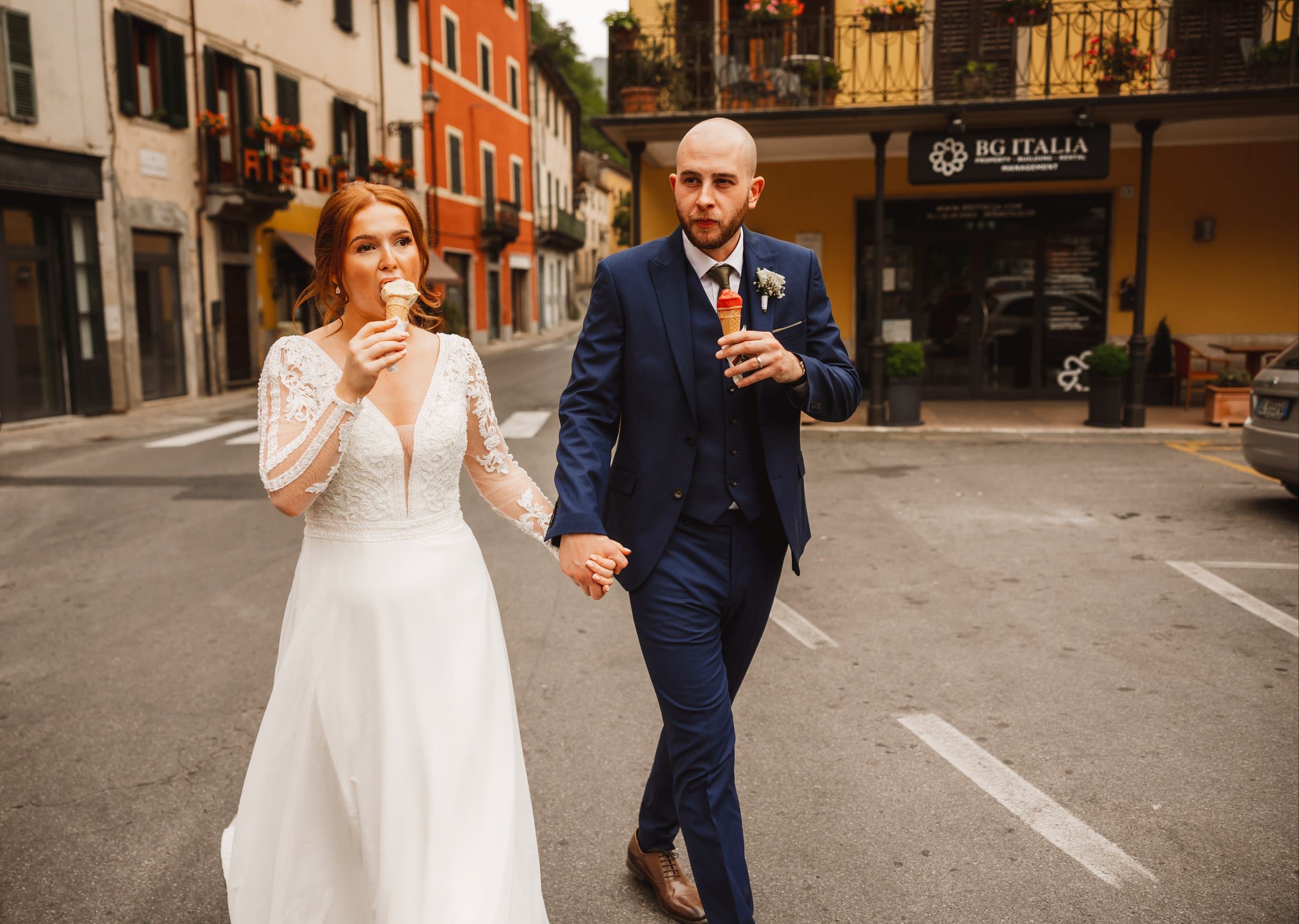 bride and groom eat ice cream cones while walking through bagni di lucca in tuscany during their italian destination wedding