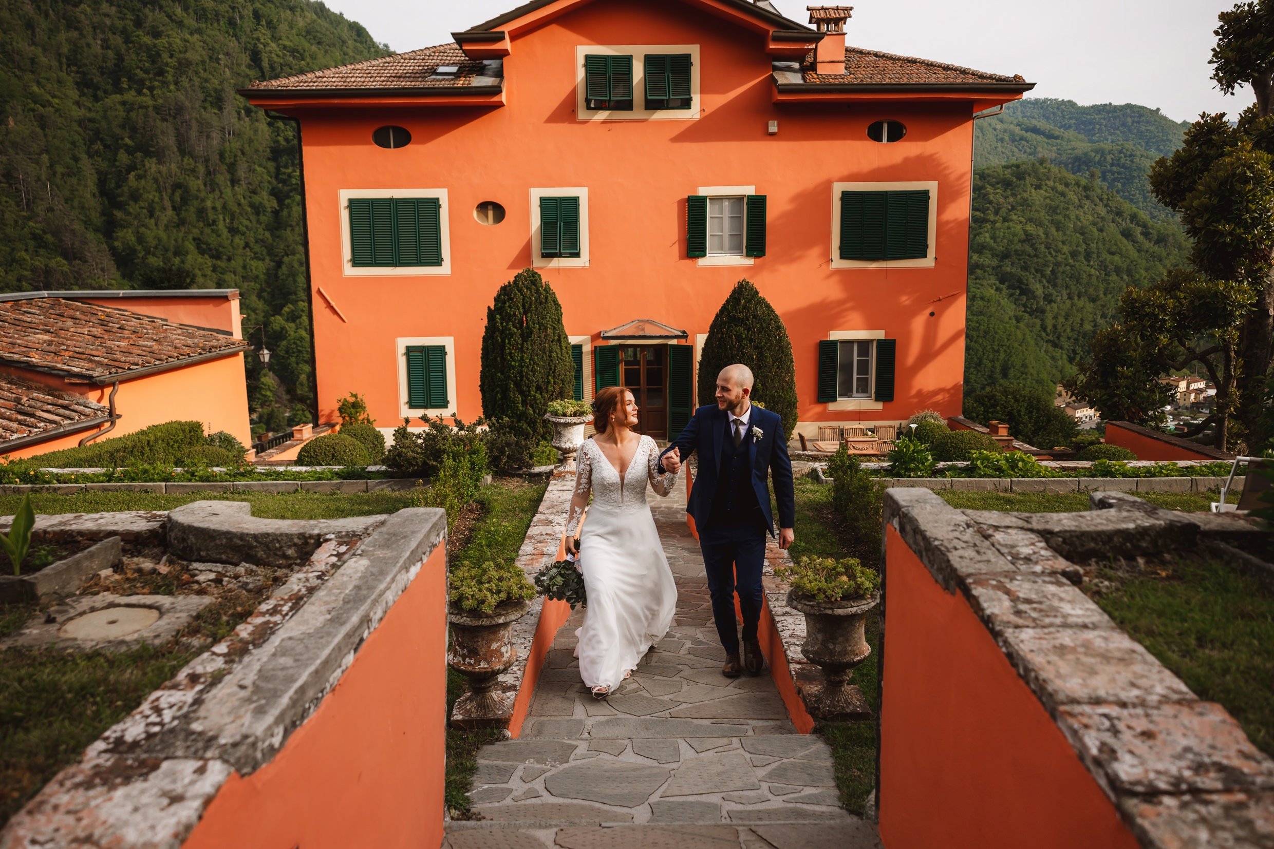 the bride and groom walking away from a villa at the agriturismo la torre italian destination wedding venue in bagni di lucca tuscany
