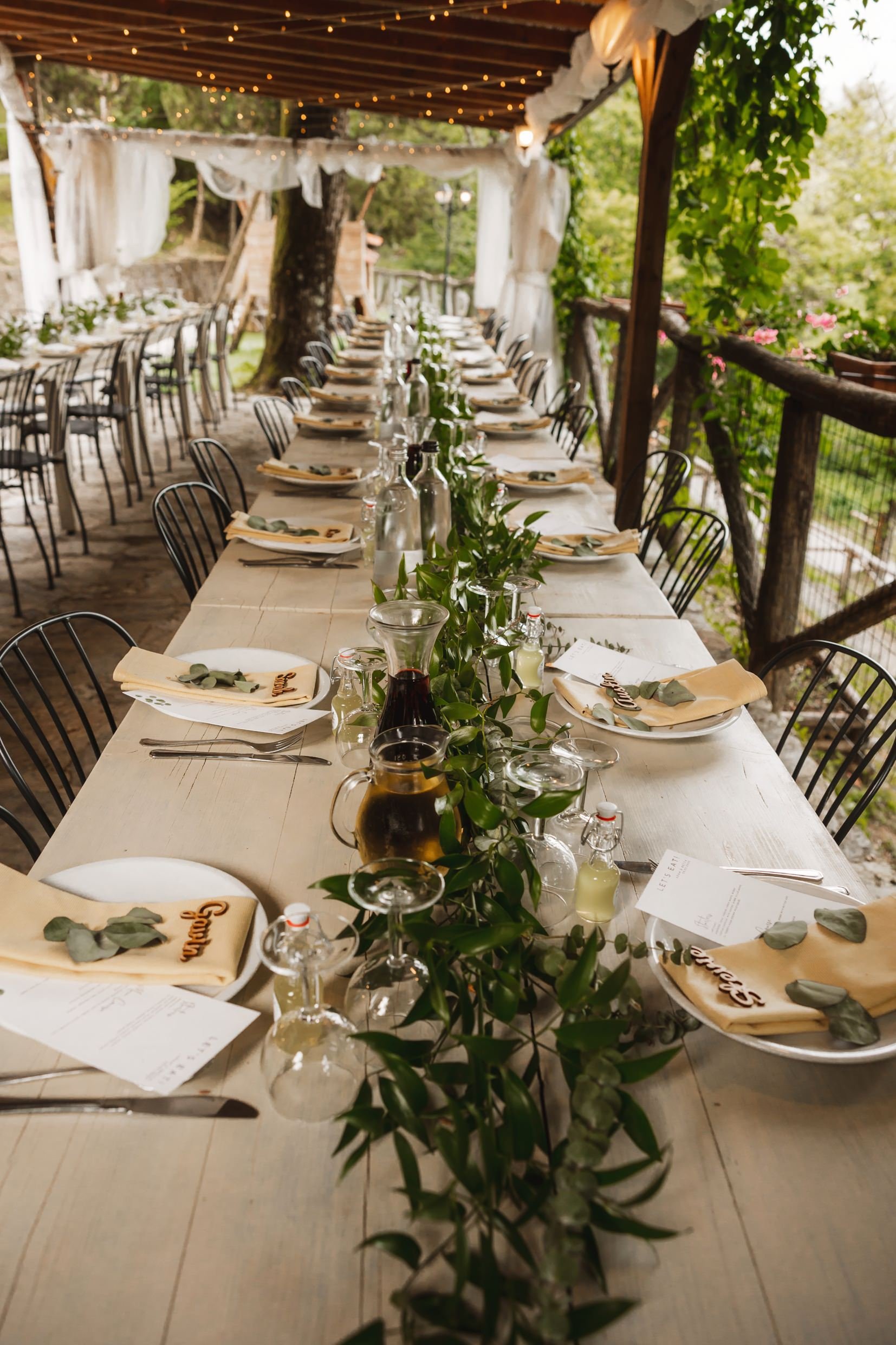 tables set for dinner with greenery and fairy lights at the agriturismo la torre italian destination wedding venue in bagni di lucca tuscany