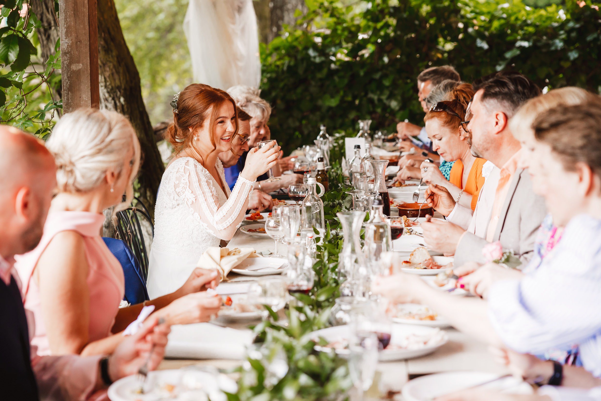 the wedding party enjoy dinner at the wedding reception at the agriturismo la torre italian destination wedding venue in bagni di lucca tuscany