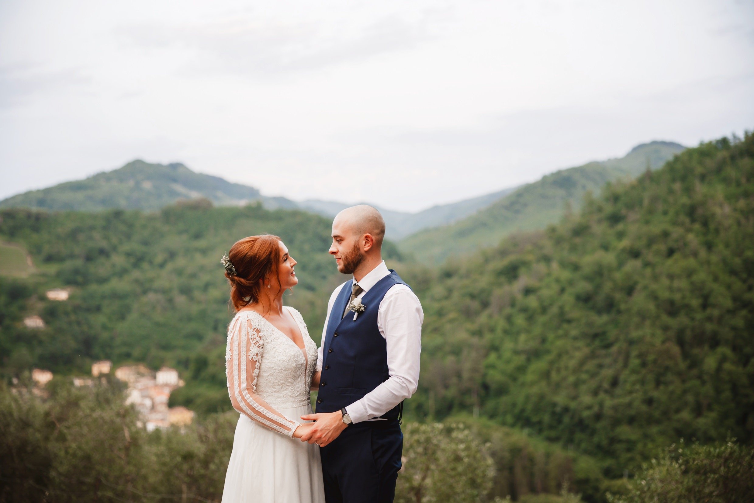 the bride and groom pose with hills in the background at the agriturismo la torre italian destination wedding venue in bagni di lucca tuscany