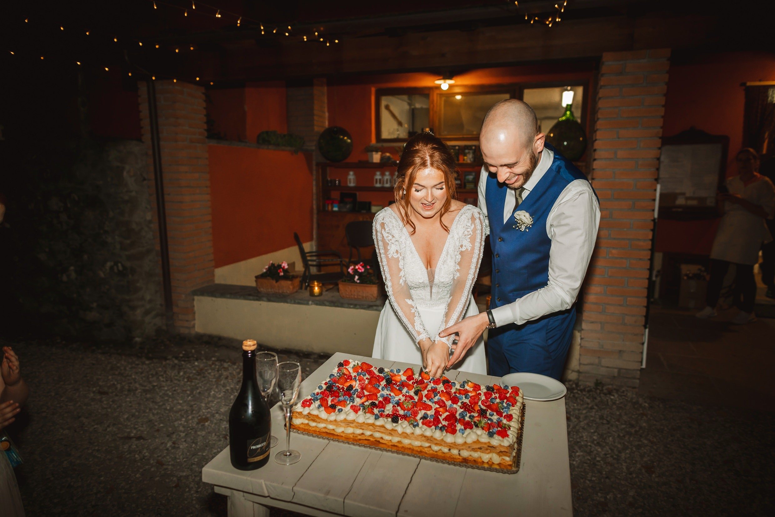 the bride and groom cut their wedding cake at the agriturismo la torre italian destination wedding venue in bagni di lucca tuscany
