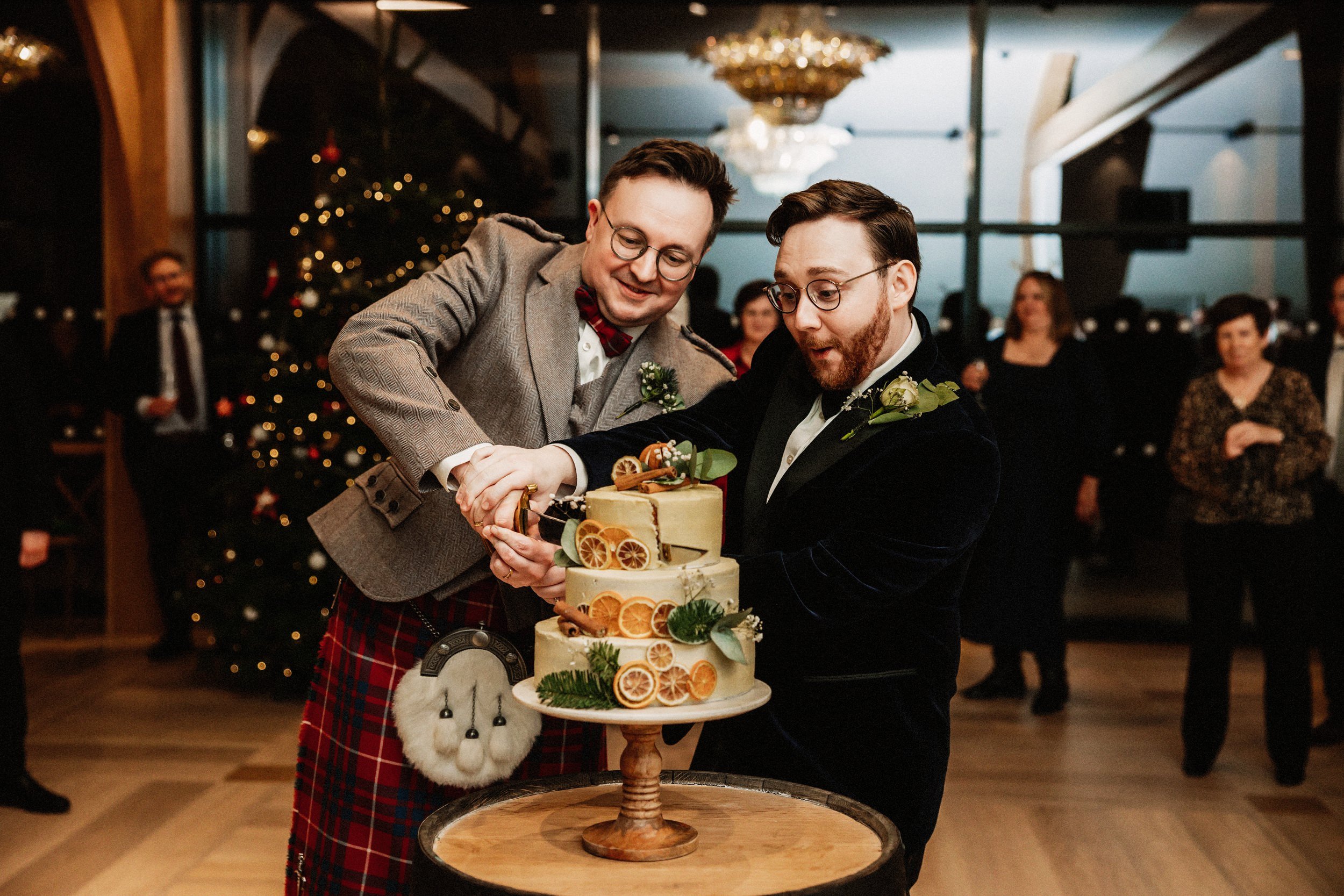  Two grooms cut creative wedding cake at Boturich caste Christmas wedding wedding photographer Scotland prices 