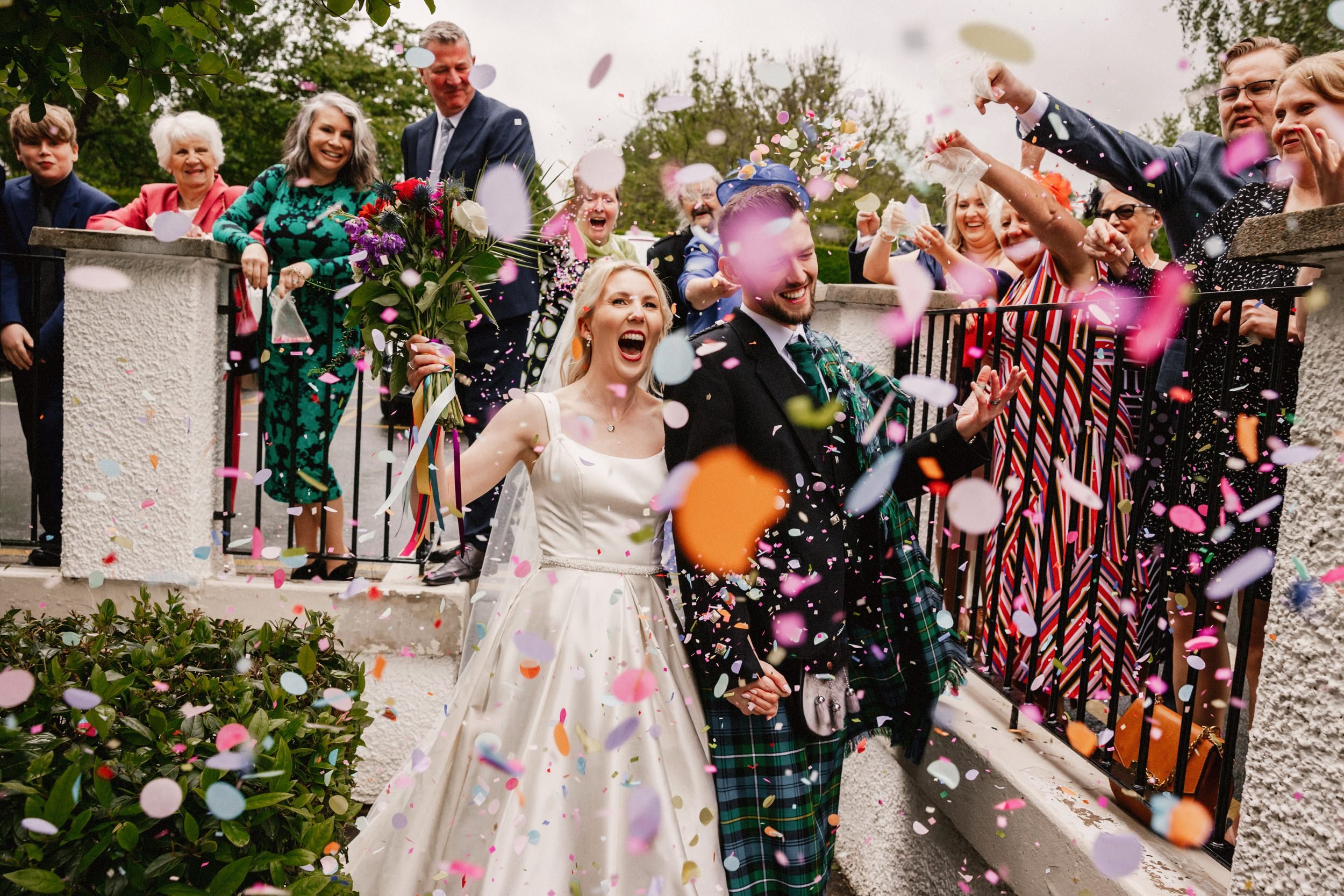 wedding photographer scotland prices captures the bride and groom walking through a shower of confetti thrown by guests