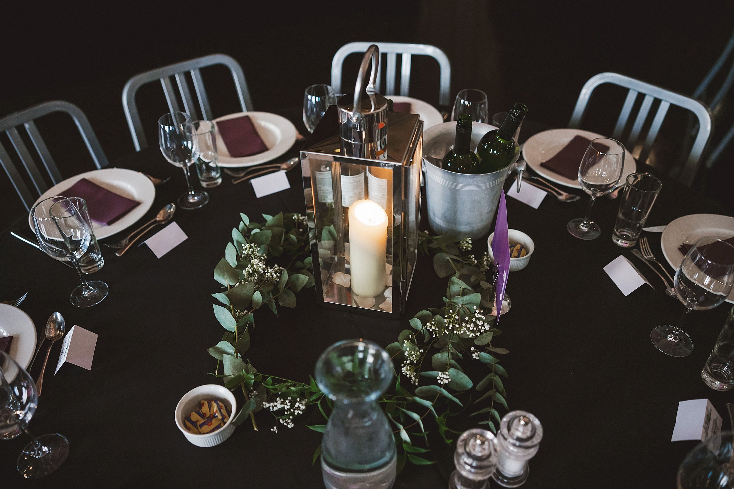 dining table set for dinner at the ghillie dhu edinburgh wedding venue with a candle and greenery centrepiece by documentary wedding photographer edinburgh scotland