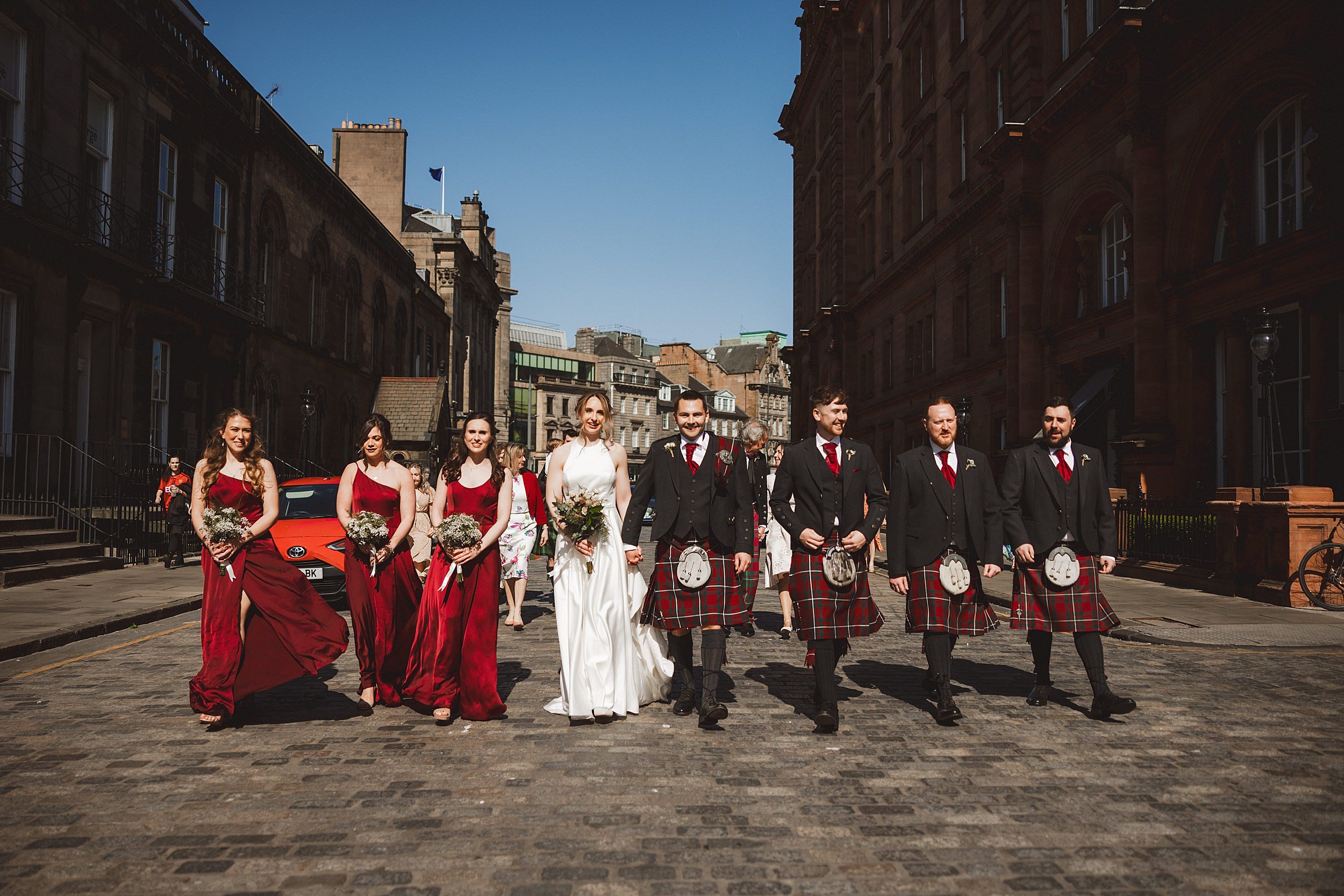 editorial shot of the wedding party walking along a street in edinburgh scotland by documentary wedding photographer edinburgh