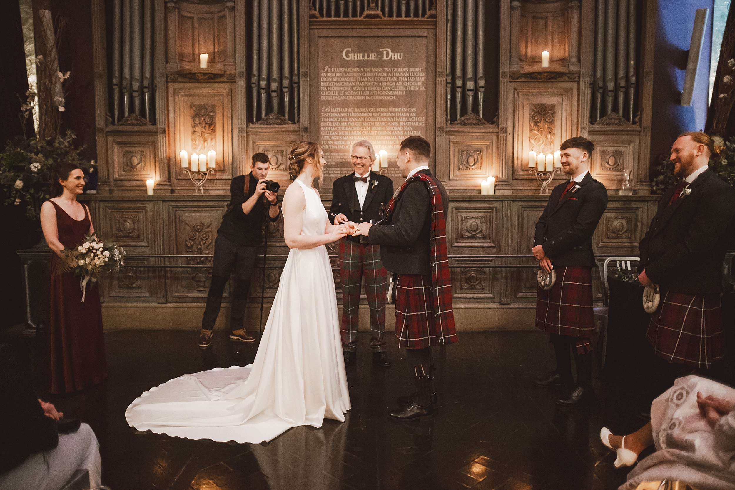 the bride and groom exchange rings as celebrant looks on during their wedding ceremony at unique wedding venue the ghillie dhu in scotland shot by documentary wedding photographer edinburgh