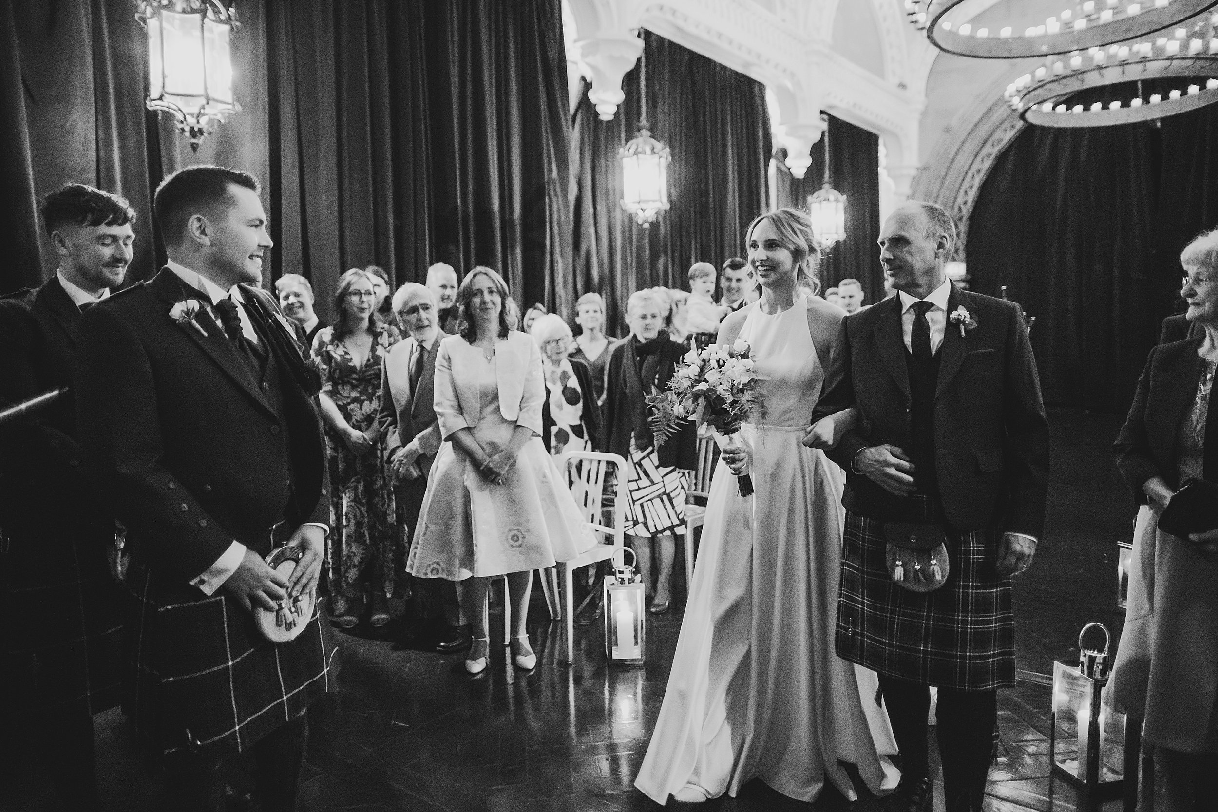 interior shot by documentary wedding photographer edinburgh of unique wedding venue the ghillie dhu showing the bride and father of the bride arriving at the head of the aisle
