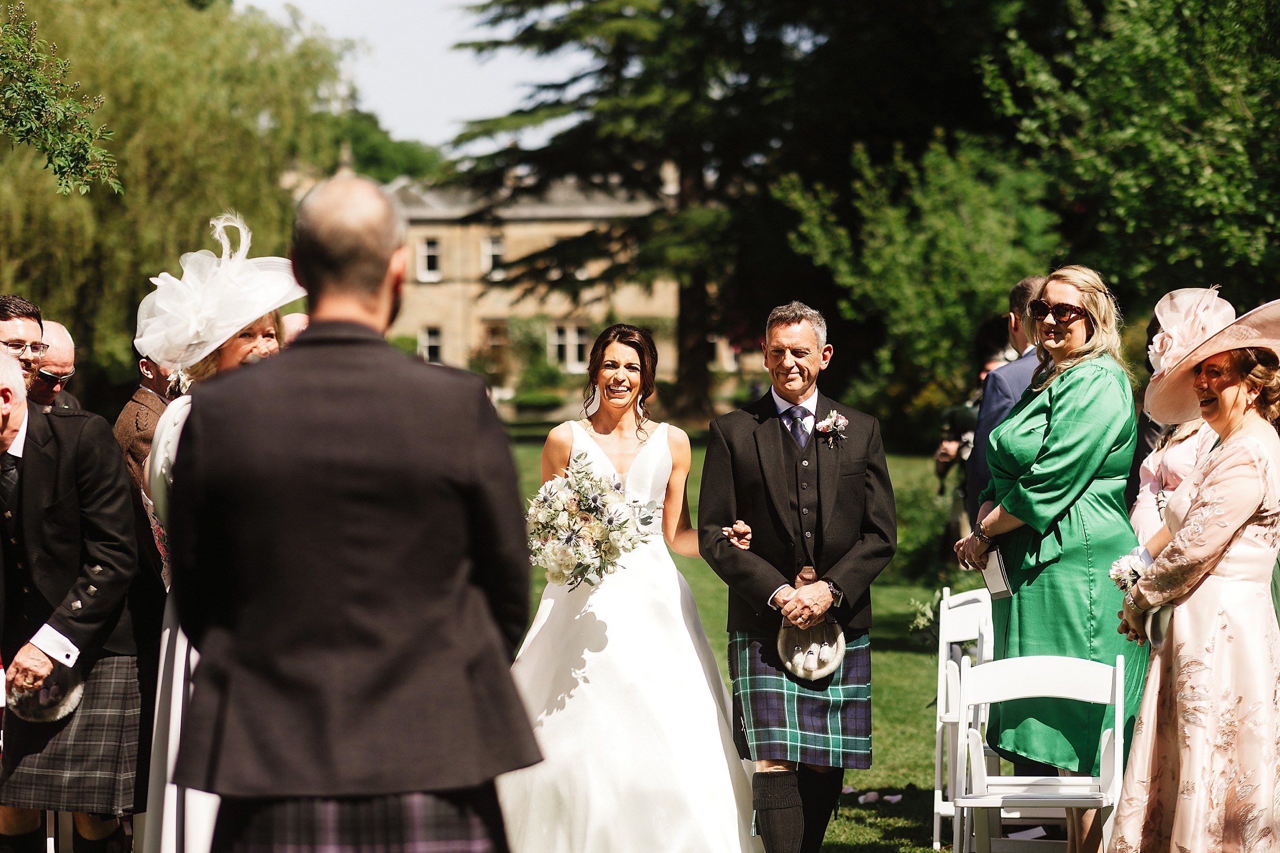 guests look on as the bride and her father walk down the aisle in the gardens of errol park wedding venue in scotland