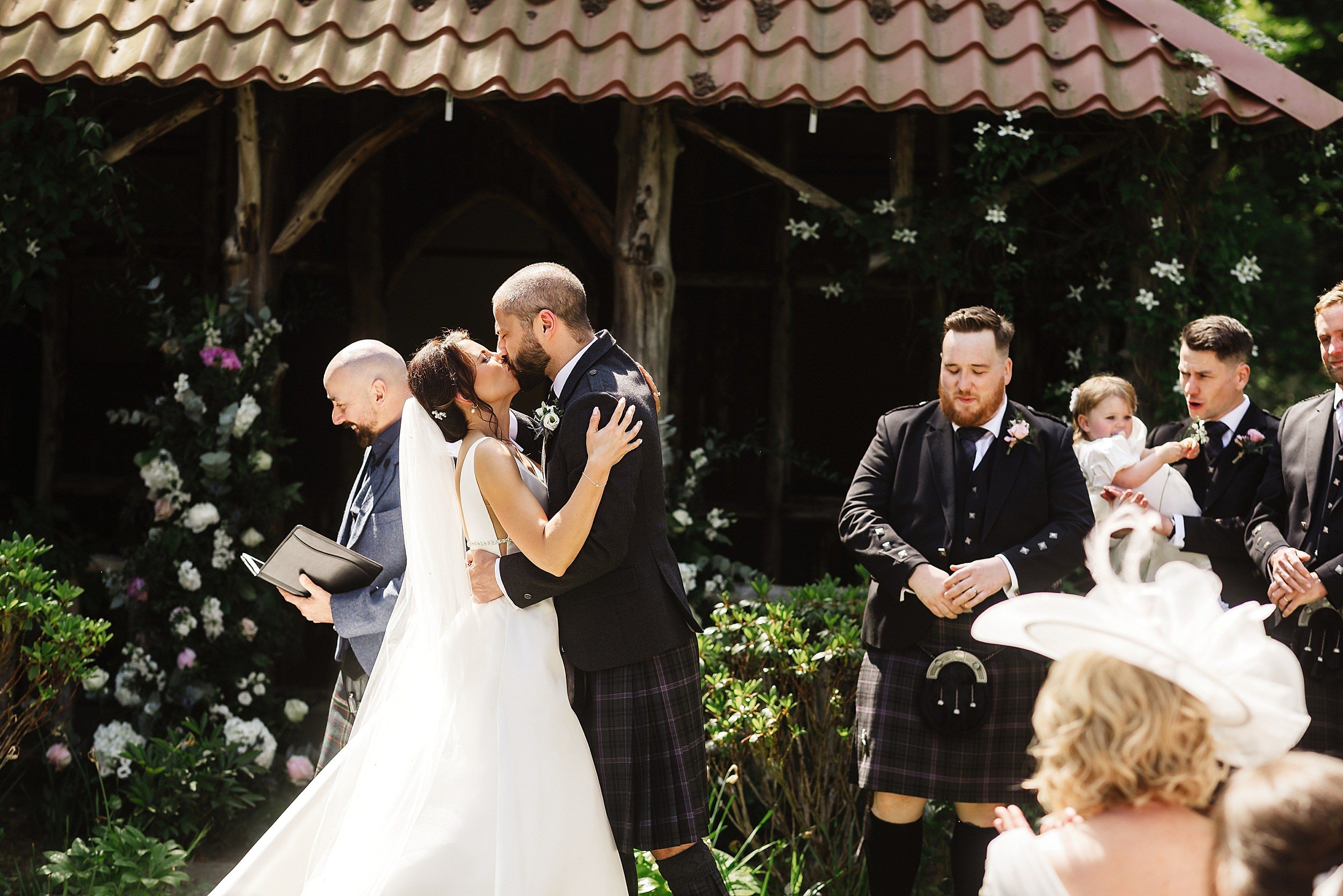 the bride and groom kiss following their wedding ceremony in the gardens of errol park wedding venue in perthshire in scotland 