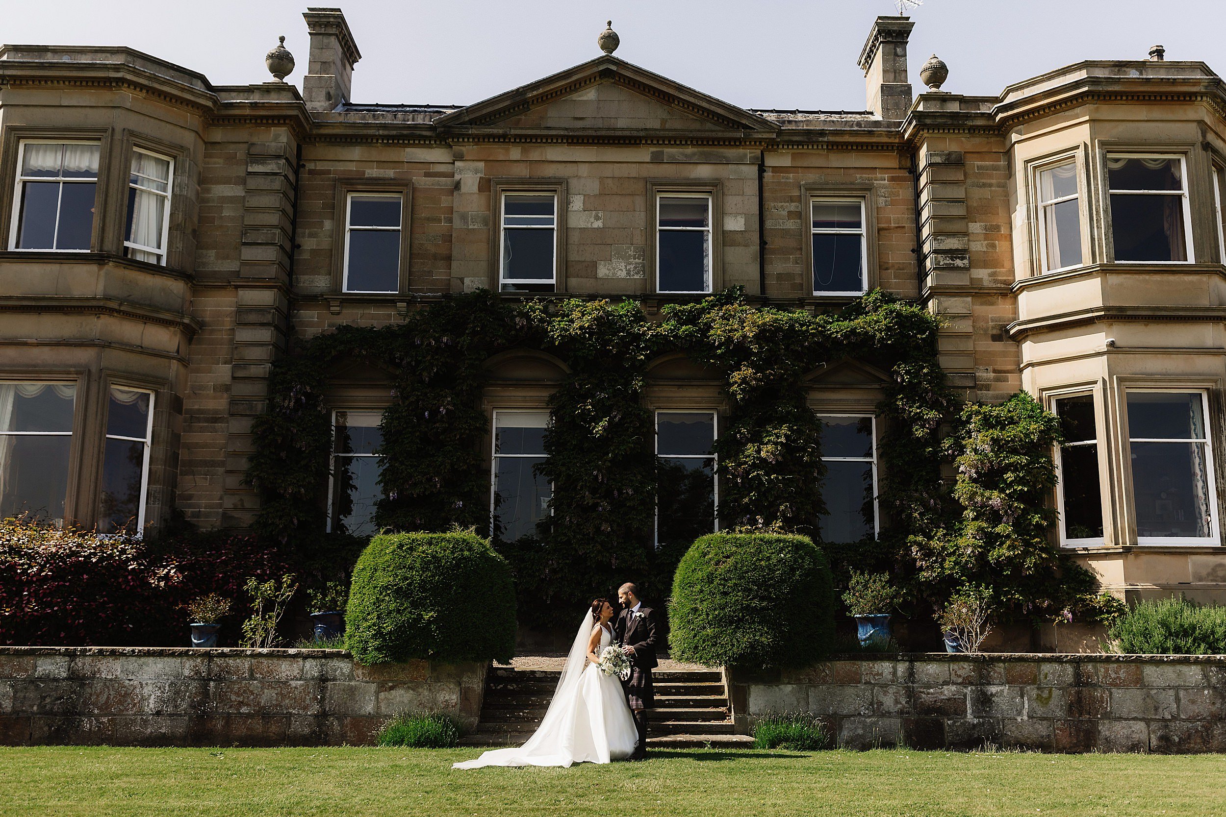 the bride and groom pose in front of stone steps outside errol park wedding venue in perthshire scotland