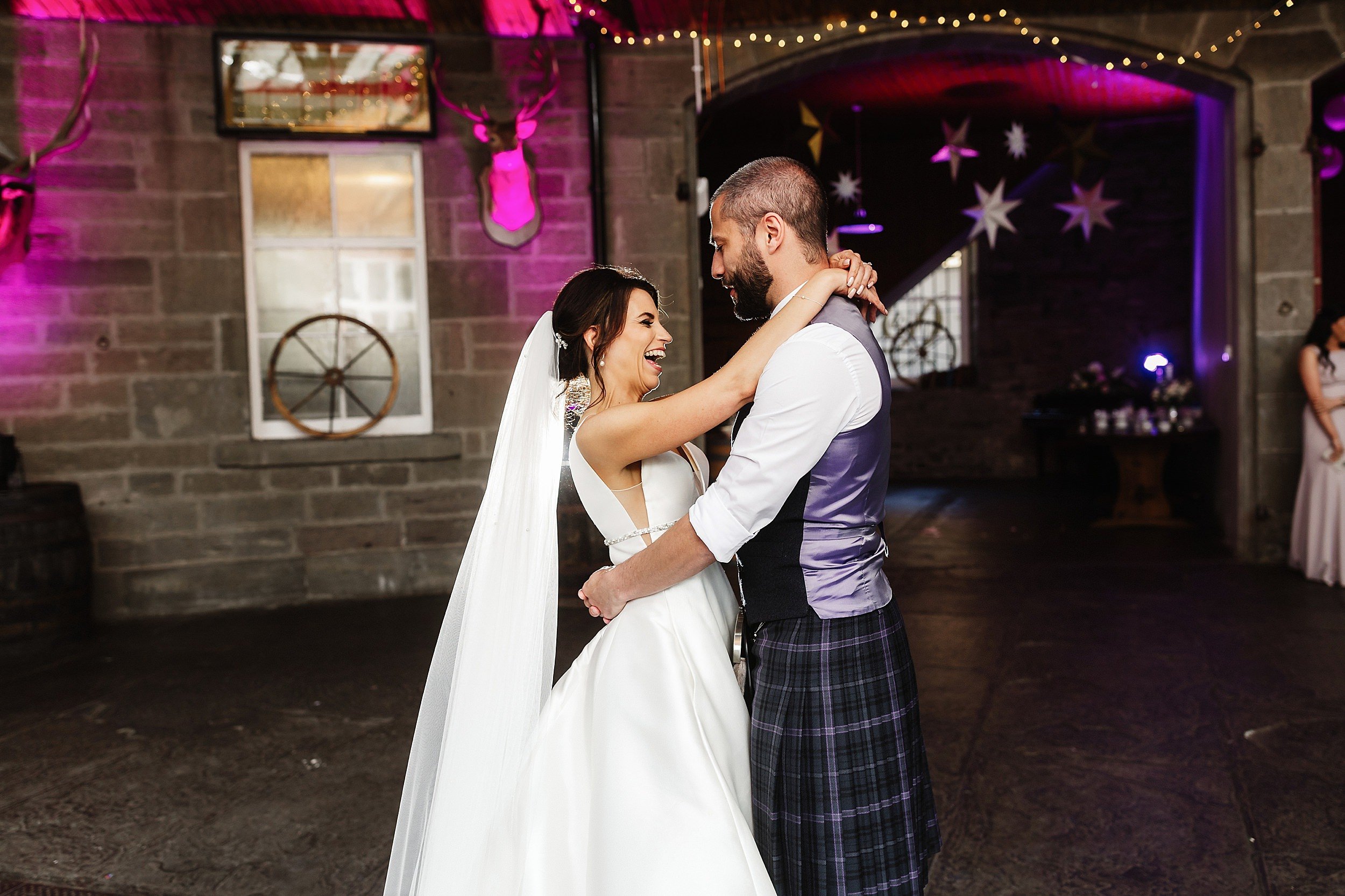 the bride and groom perform their first dance in a room with a stone floor and fairy lights in errol park wedding venue in perthshire in scotland