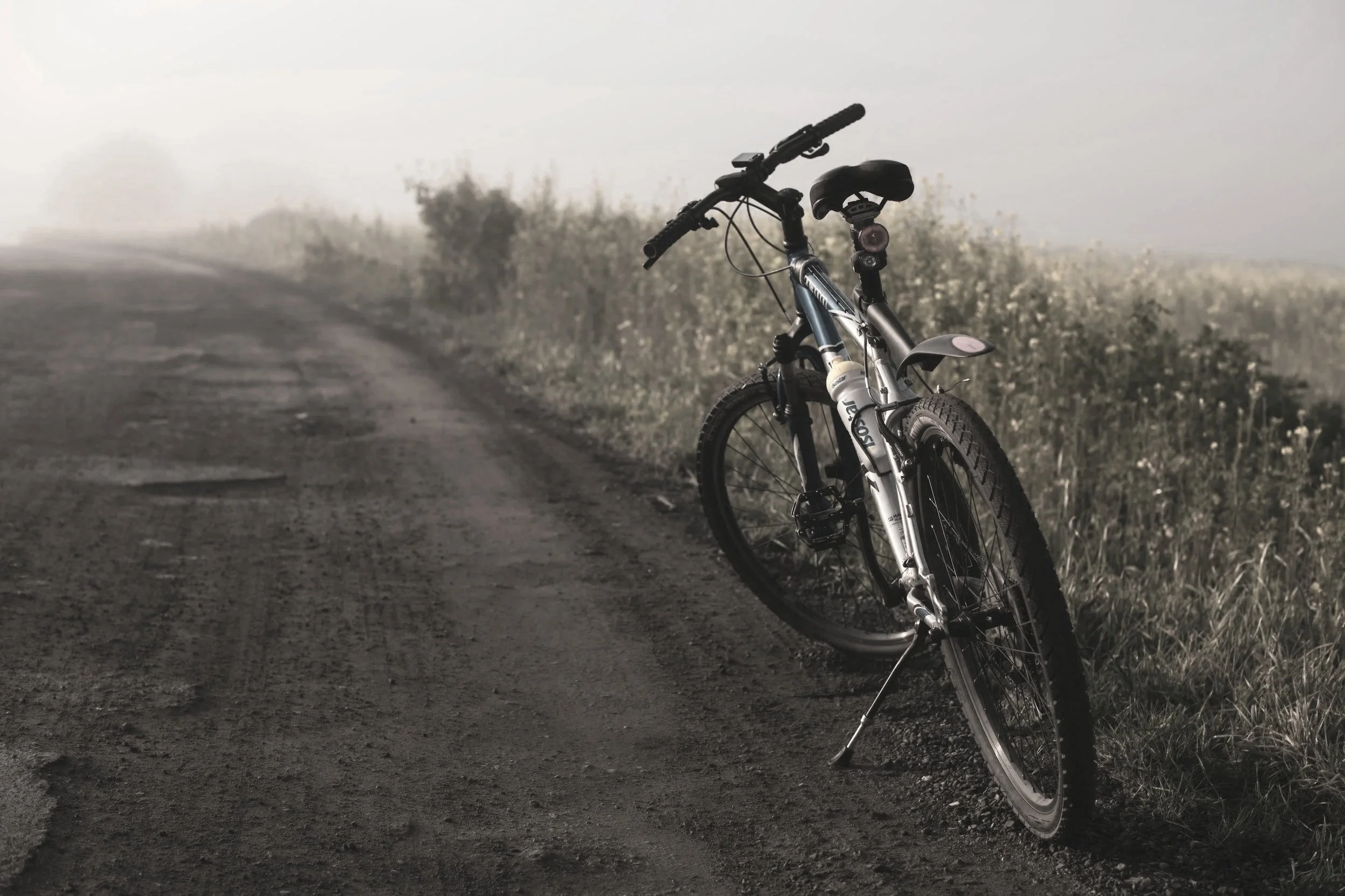 A bicycle resting on a quiet, fog-covered dirt path, representing the uncertain terrain of starting EMDR therapy