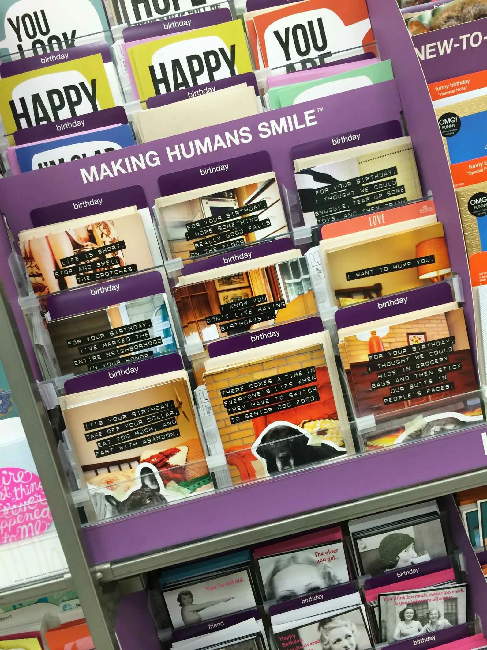 A display of greeting cards with various colors and messages, mainly for birthdays, with some cards featuring images of dogs and puppies.