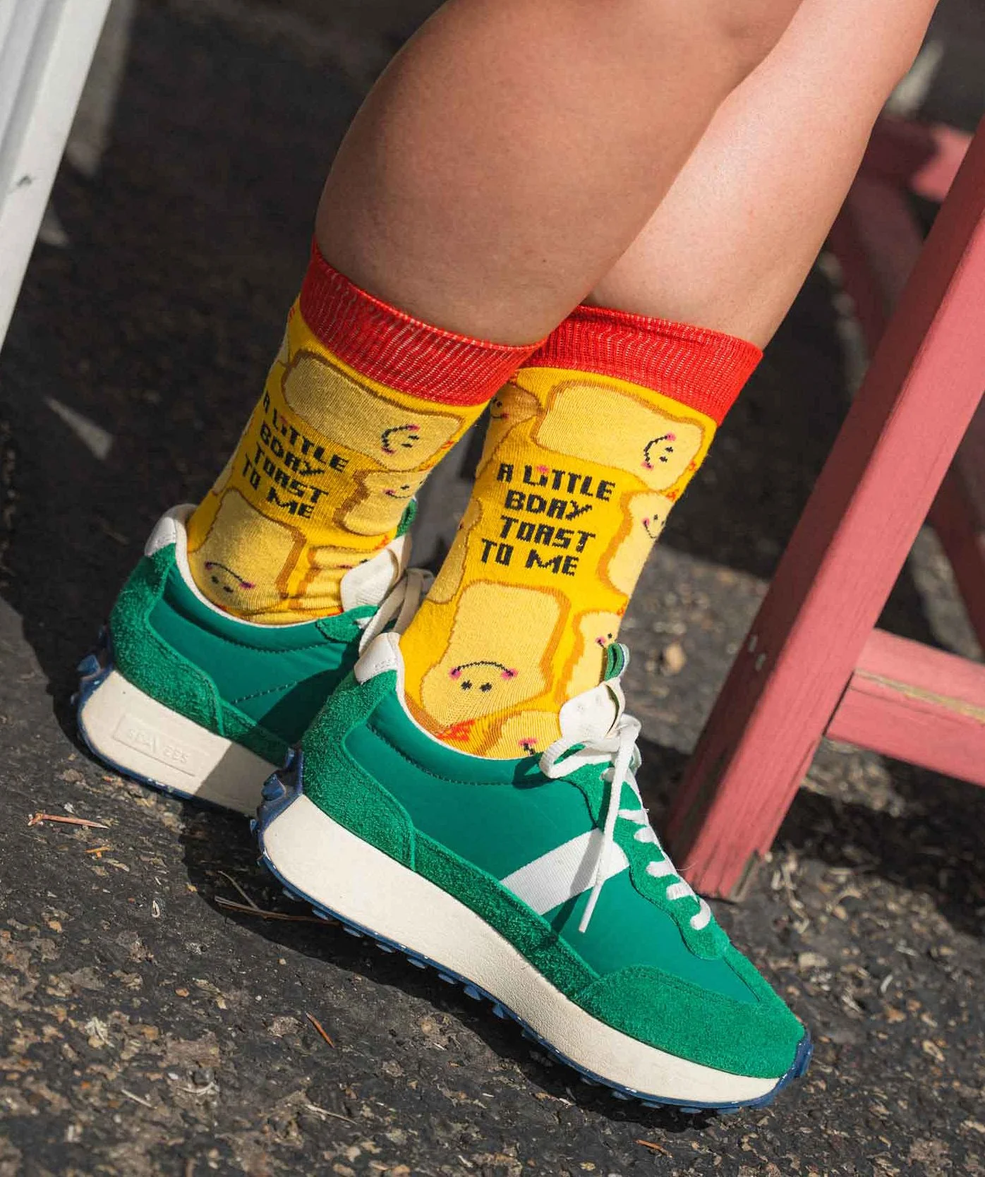 Person wearing green sneakers and yellow socks with cartoon bread and the words "A little birthday toast".