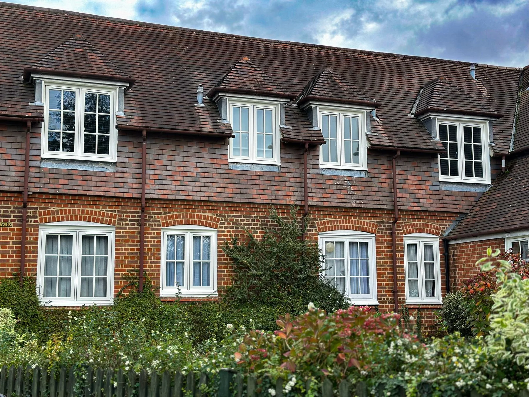 White casement windows with Georgian bars on a row of brick cottages, installed by Oakwood Windows