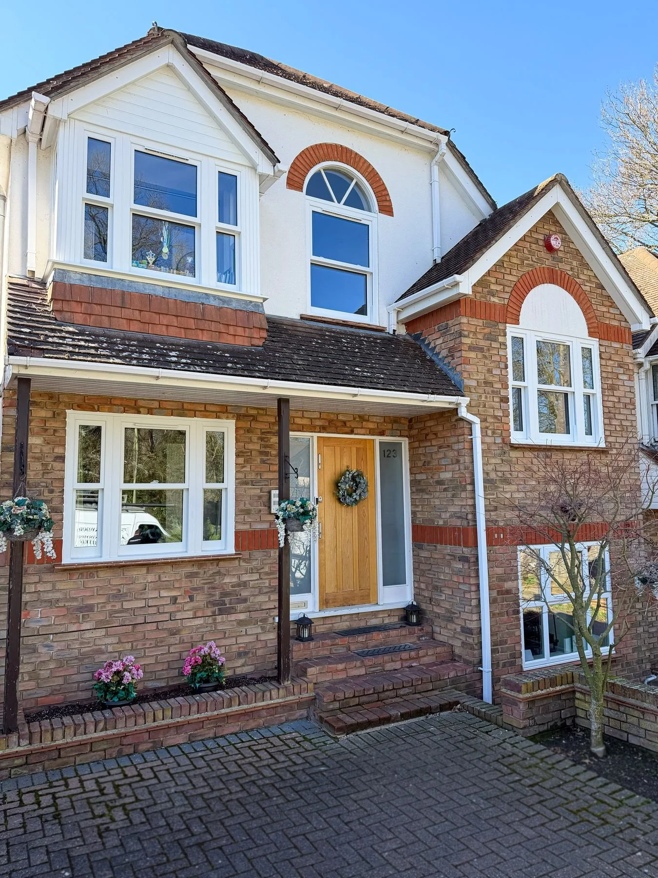 White uPVC windows with an arched feature window on a brick family house, installed by Oakwood Windows