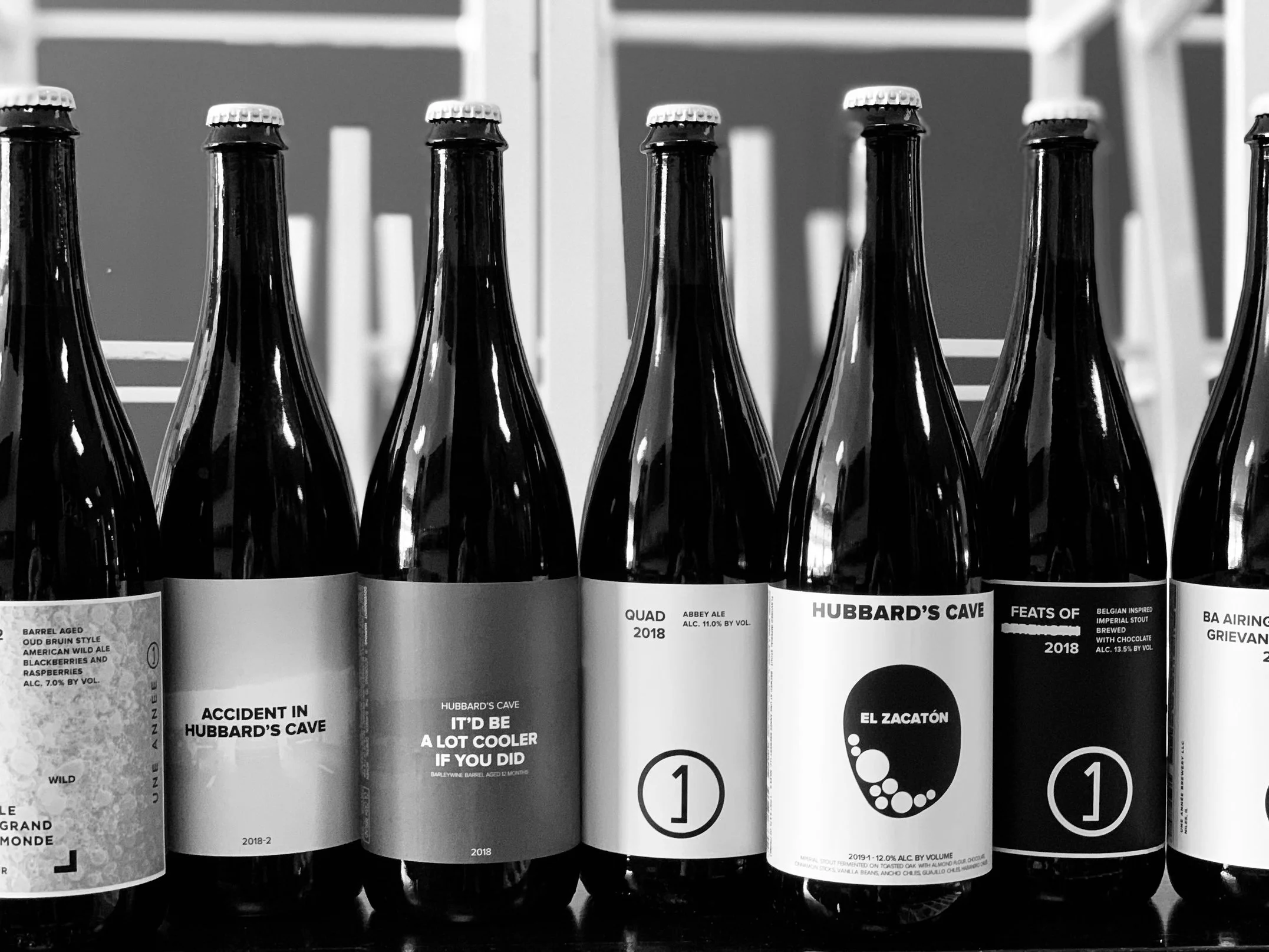 Close-up of several dark beer bottles with various labels, some featuring 'Hubbard's Cave' branding.