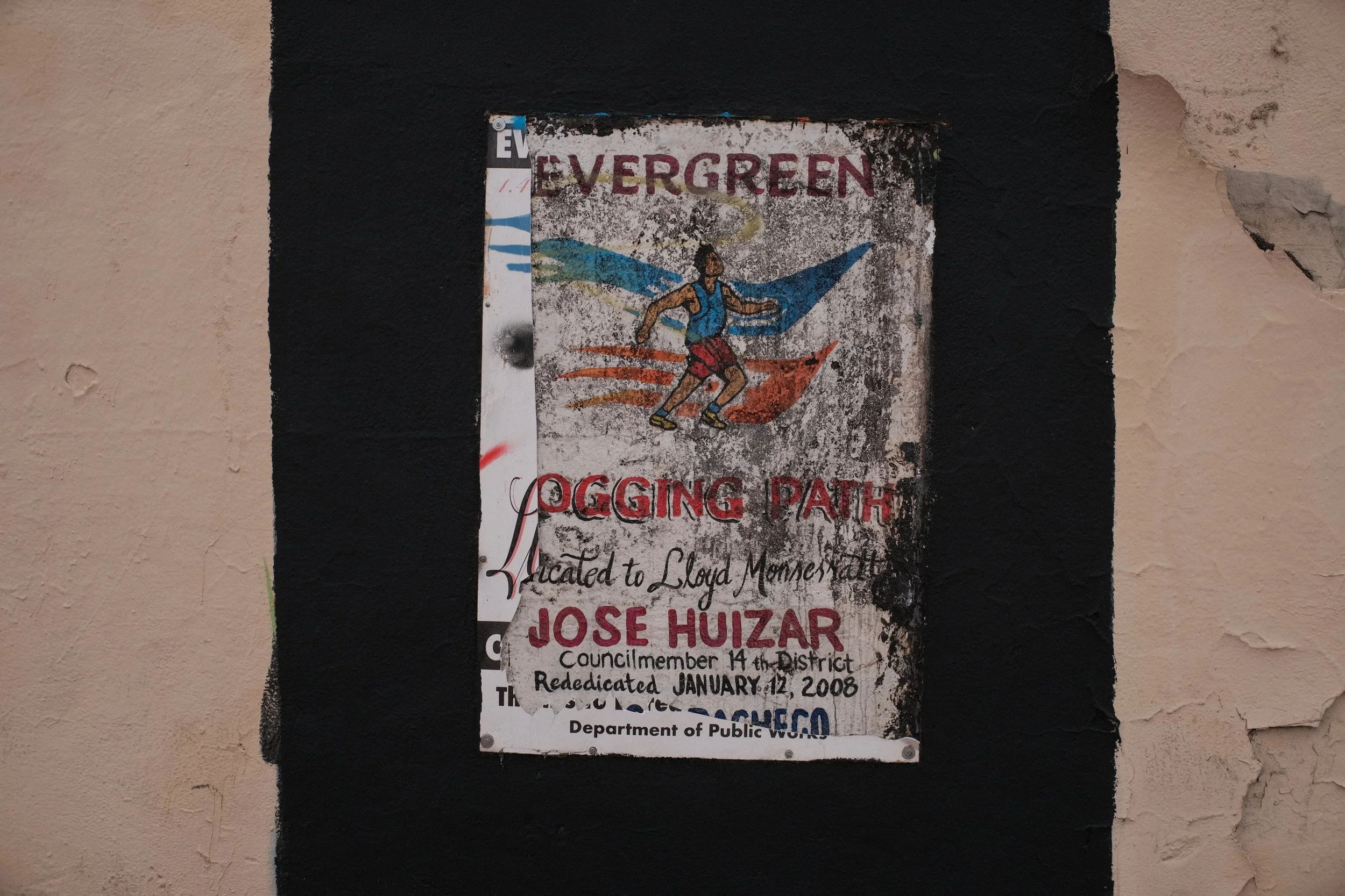 Old, weathered poster taped to a wall, featuring a graphic of a person running with blue wings, and text about a program called Evergreen, linked to Lloyd Montestad and Jose Huizar.