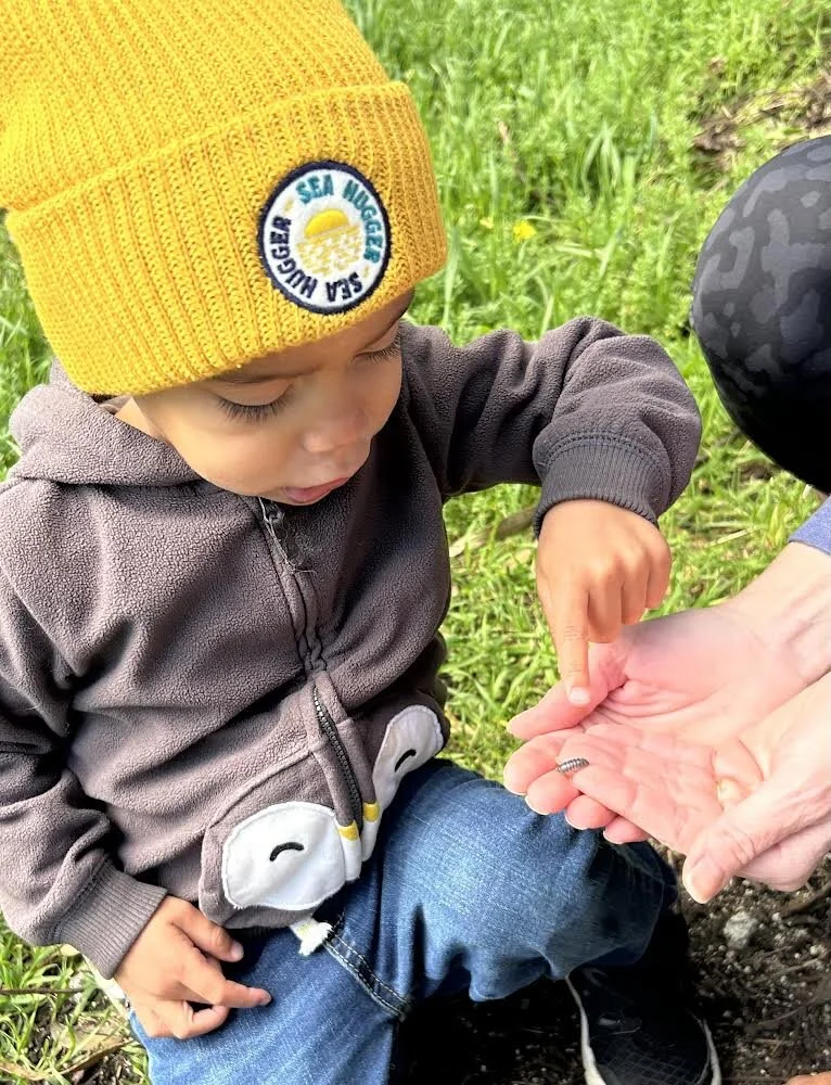 Young child wearing a yellow Sea Hugger beanie, exploring nature while promoting sustainable, plastic-free clothing options.
