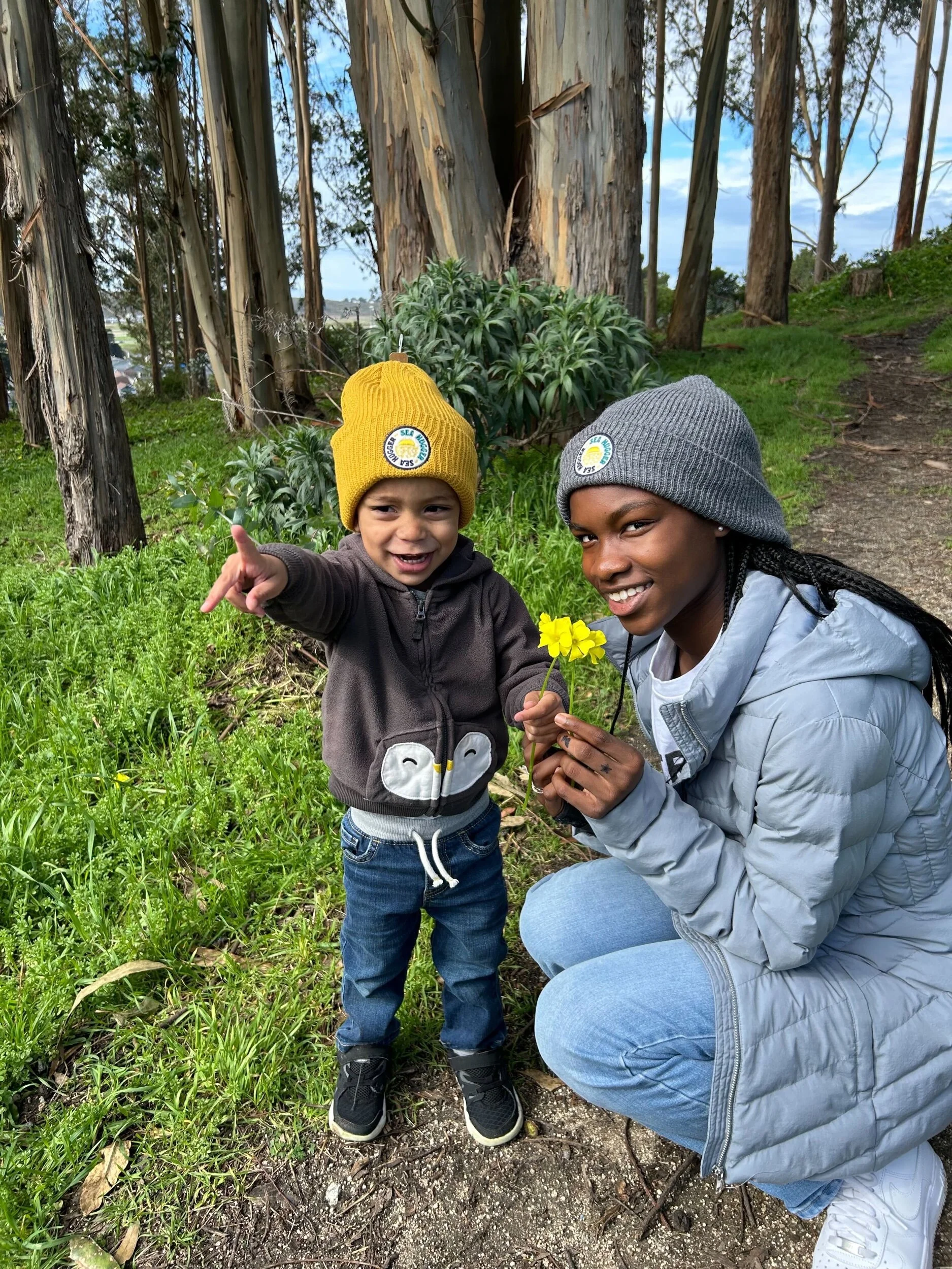 Eco-conscious child and teen wearing Sea Hugger plastic-free beanies in a forest, promoting sustainable fashion for kids and adults.
