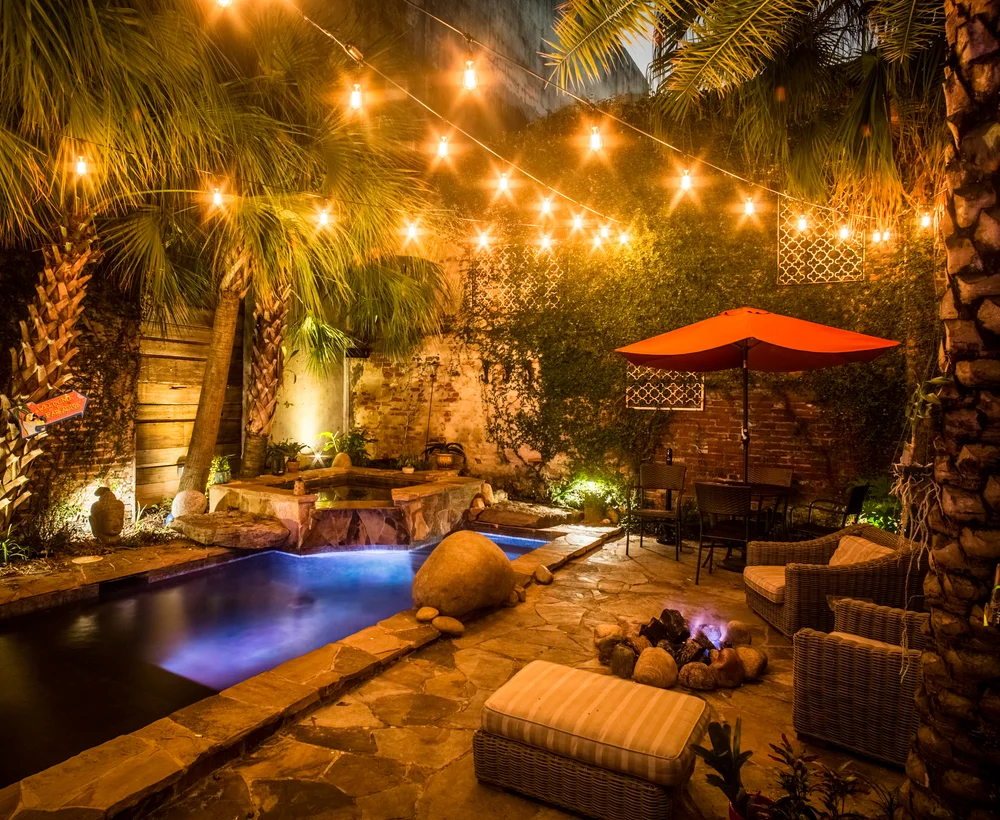 Privé courtyard and pool under string lights at night