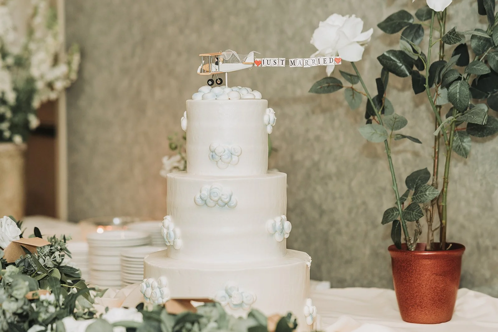 Aviation themed wedding cake with clouds and airplane topper.
