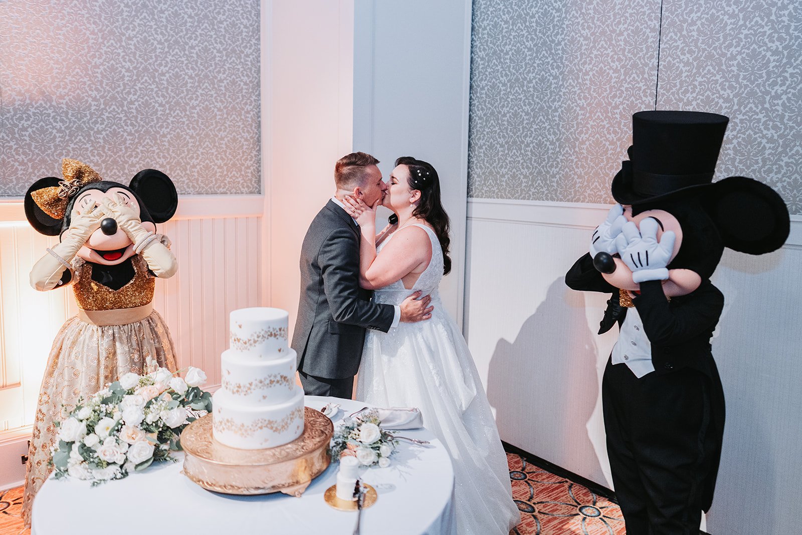 Mickey and Minnie helping couple cut wedding cake at Disney Boardwalk ballroom reception.
